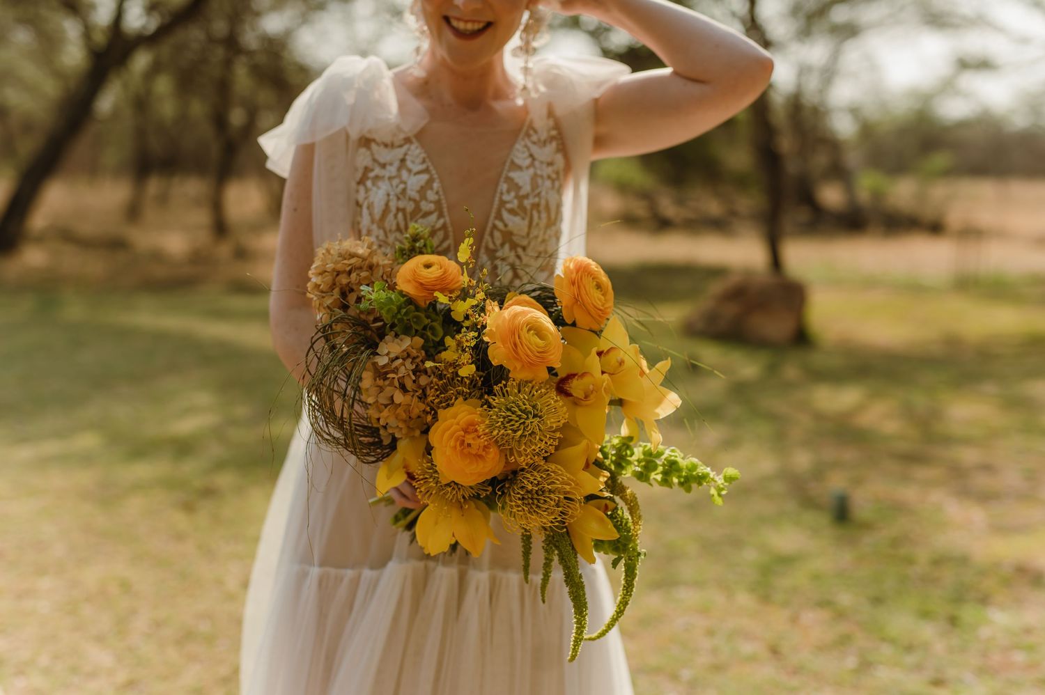 Close-up of bright yellow sunflower wedding bouquet against natural outdoor background.