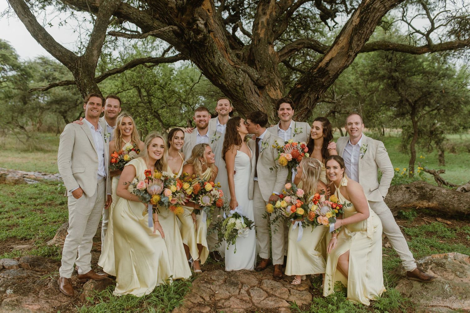 Wedding party poses together outdoors with colorful bouquets and coordinated attire.