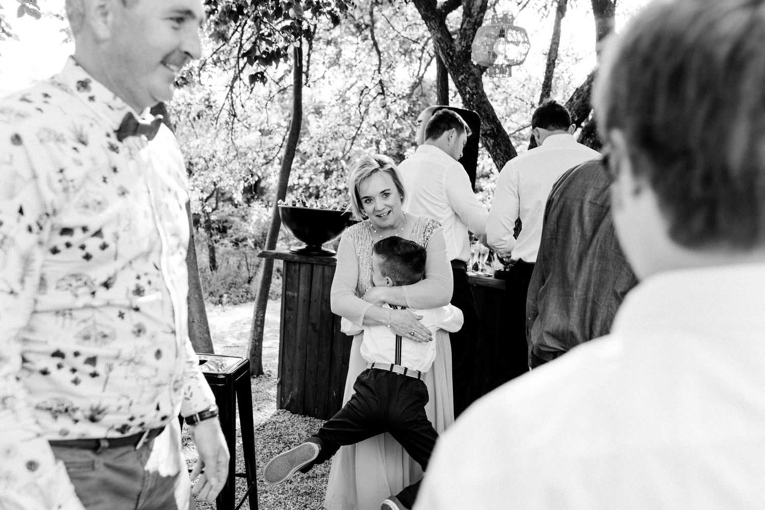 Black and white candid photo of guests enjoying an outdoor wedding celebration.