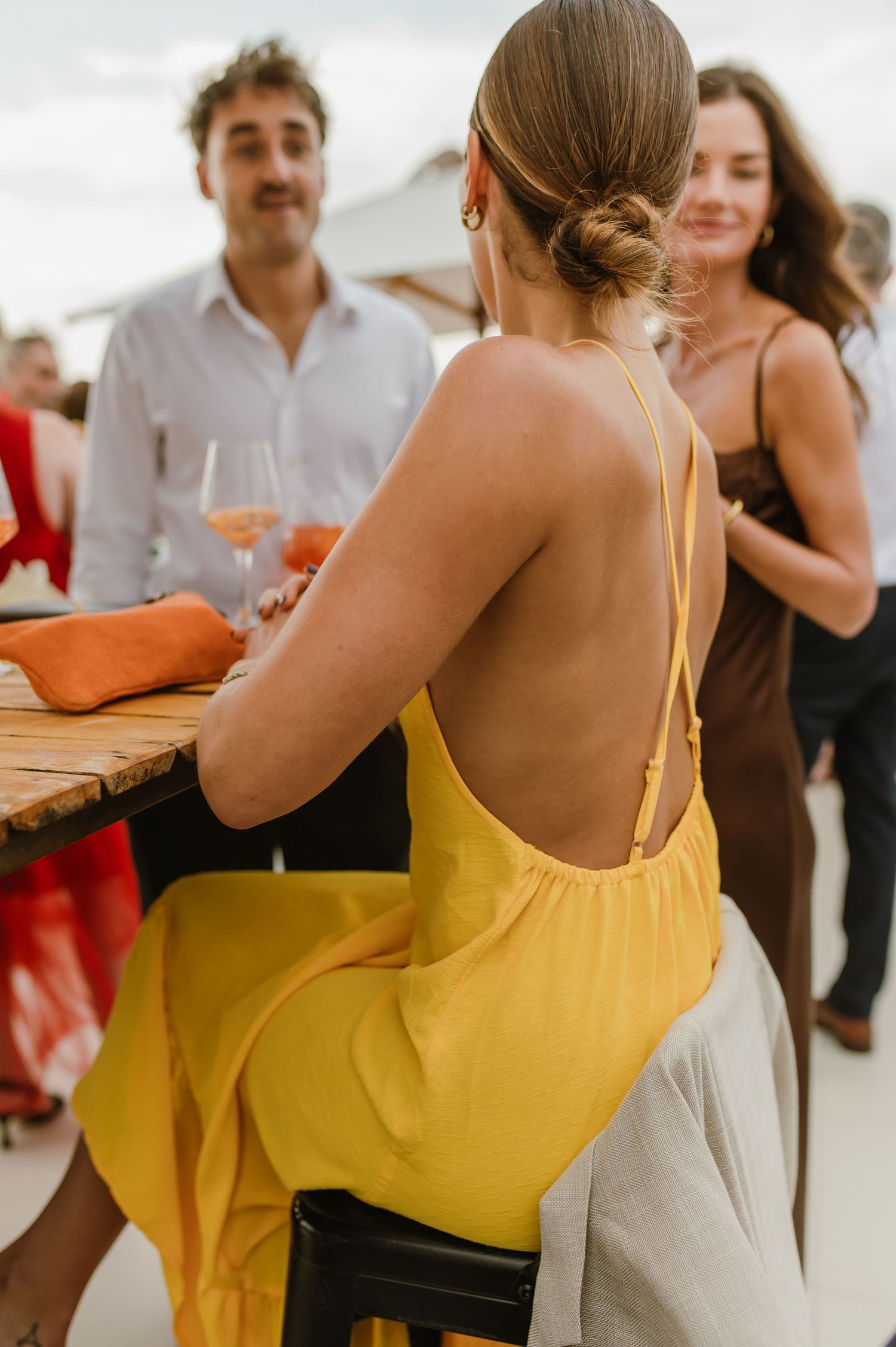 Wedding guests in bright summer attire socializing at an outdoor reception.