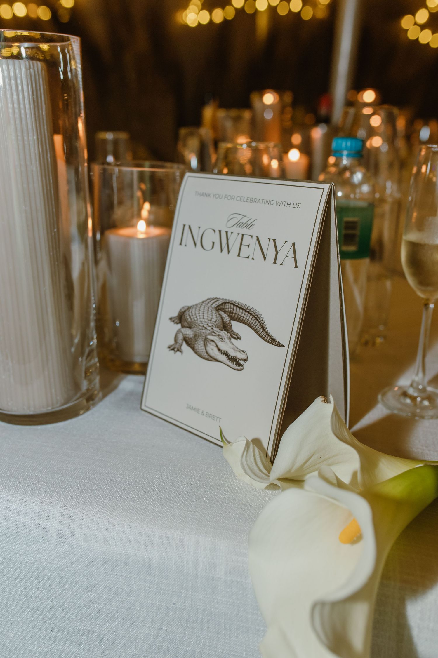 Wedding table settings with animal-themed place cards and white candles.