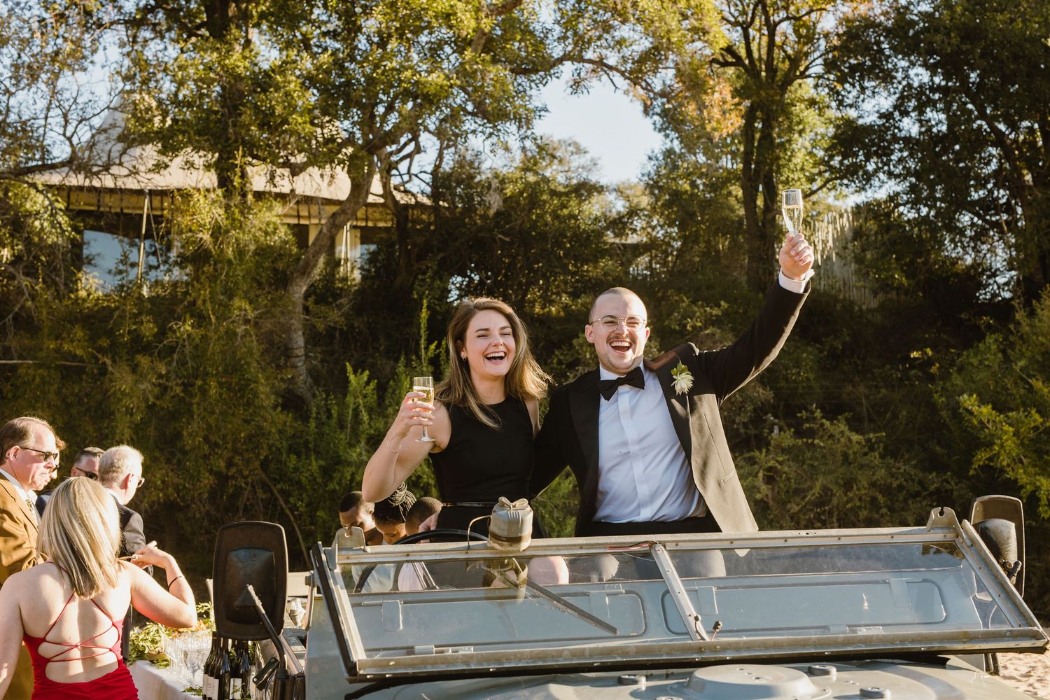 Wedding celebration on a sandy beach with trees and golden sunlight creating a warm atmosphere.