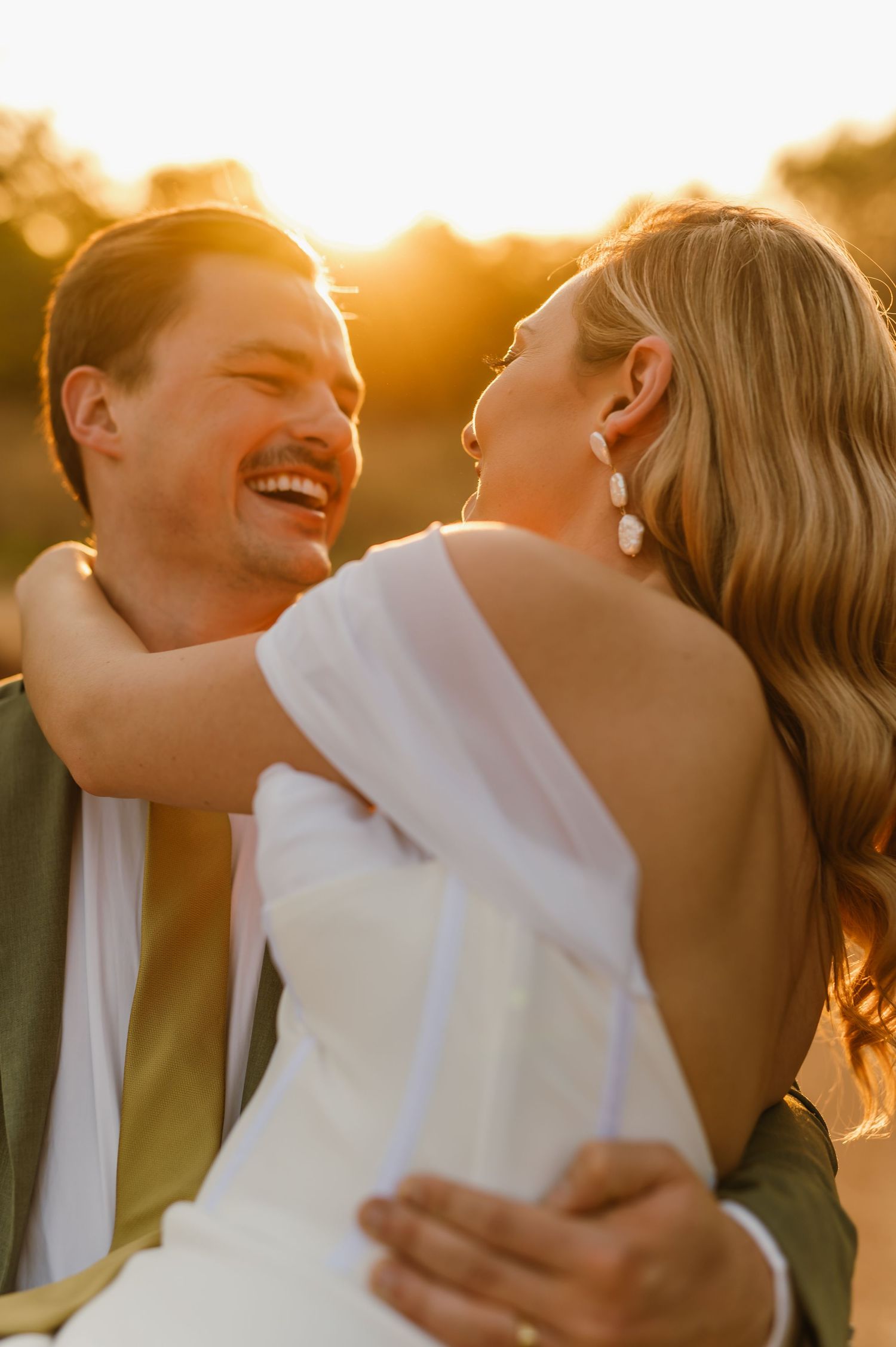 Candid moment of laughter and love captured in golden sunset light.