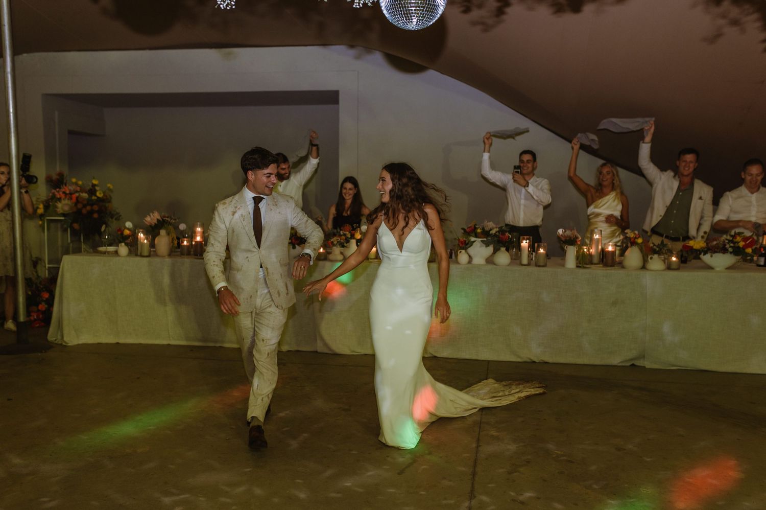 Guests celebrate on the dance floor under disco balls at a nighttime wedding reception.
