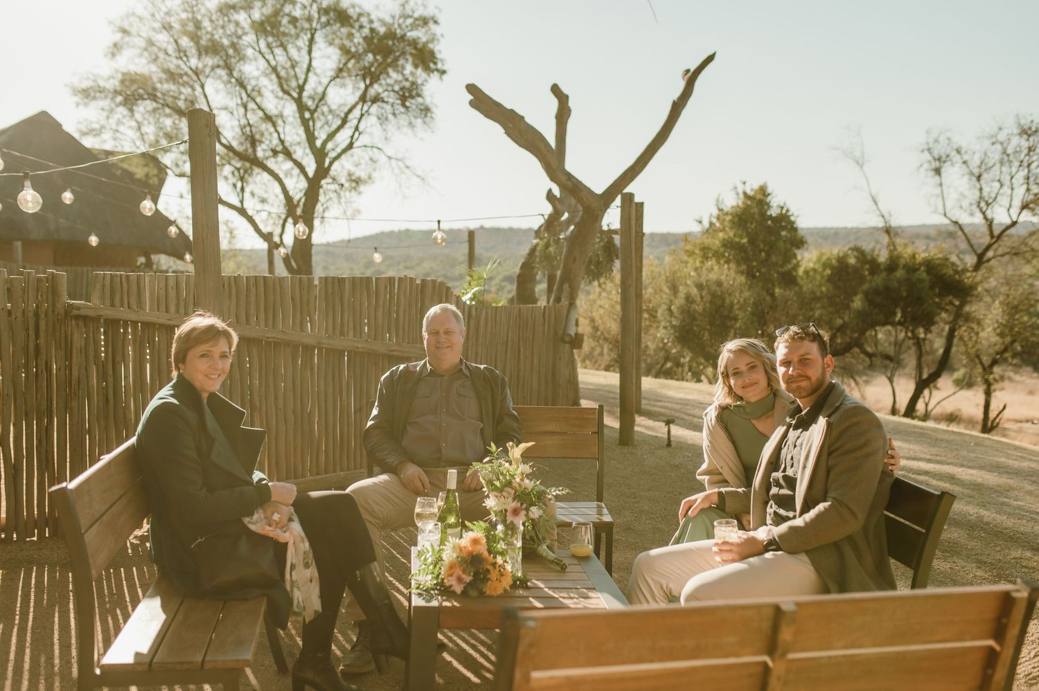 Three guests enjoying drinks at an outdoor seating area with desert landscape behind them.