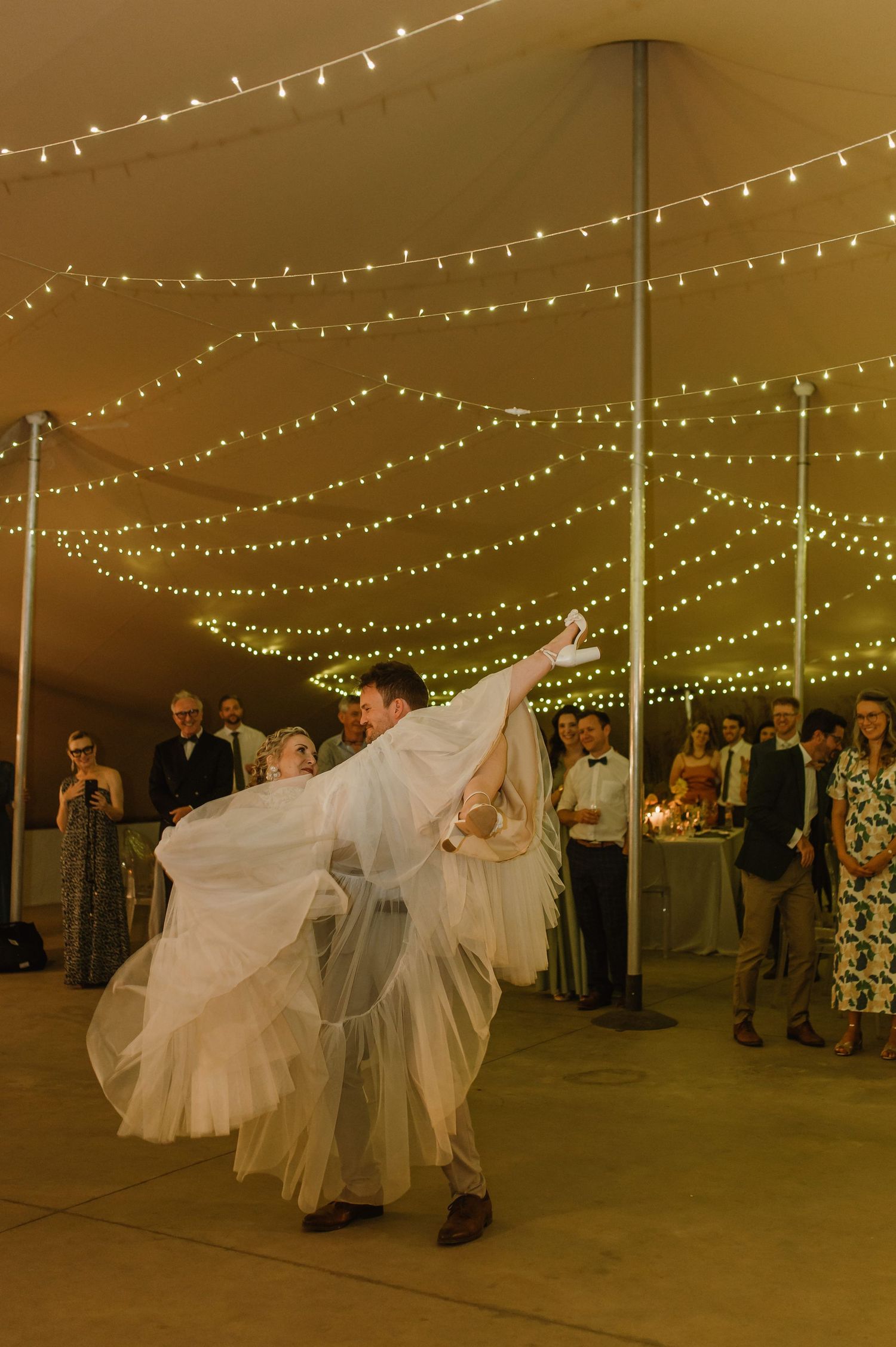 Wedding celebration with couples dancing under canopy of twinkling lights.