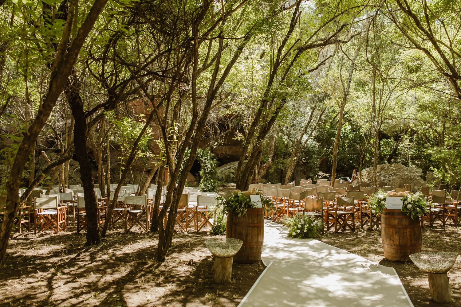 A tree-lined pathway with dappled sunlight creates a natural outdoor wedding venue setting.