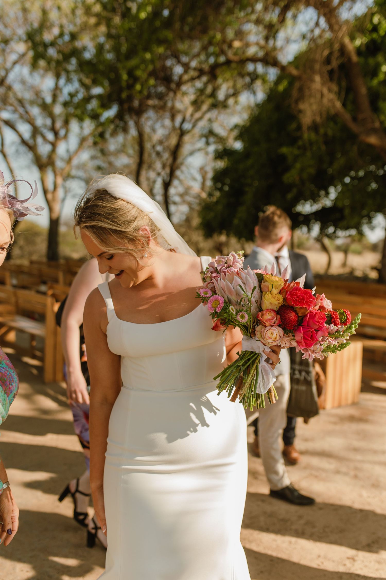 Close-up details of a white wedding dress and vibrant red floral bouquet.