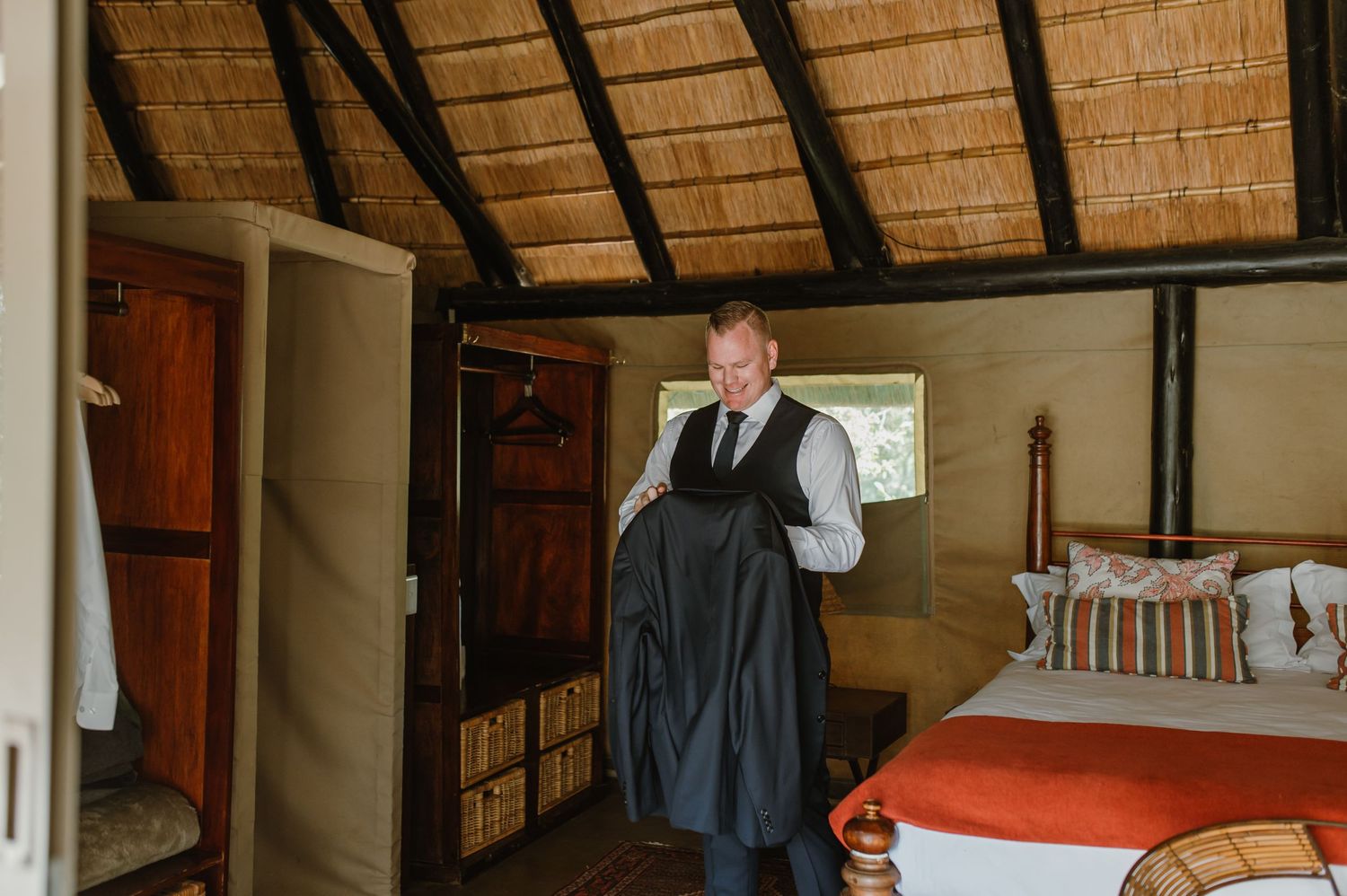 Interior view of a rustic bedroom with thatched roof and wooden furniture.