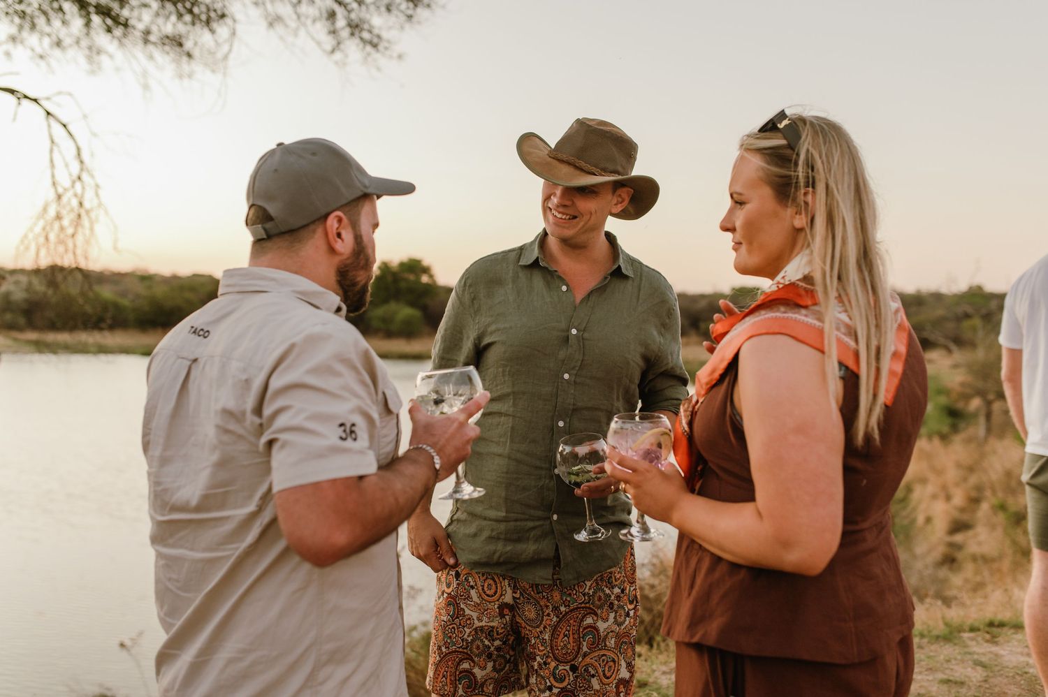 Group chatting and drinking at a casual outdoor party near water.