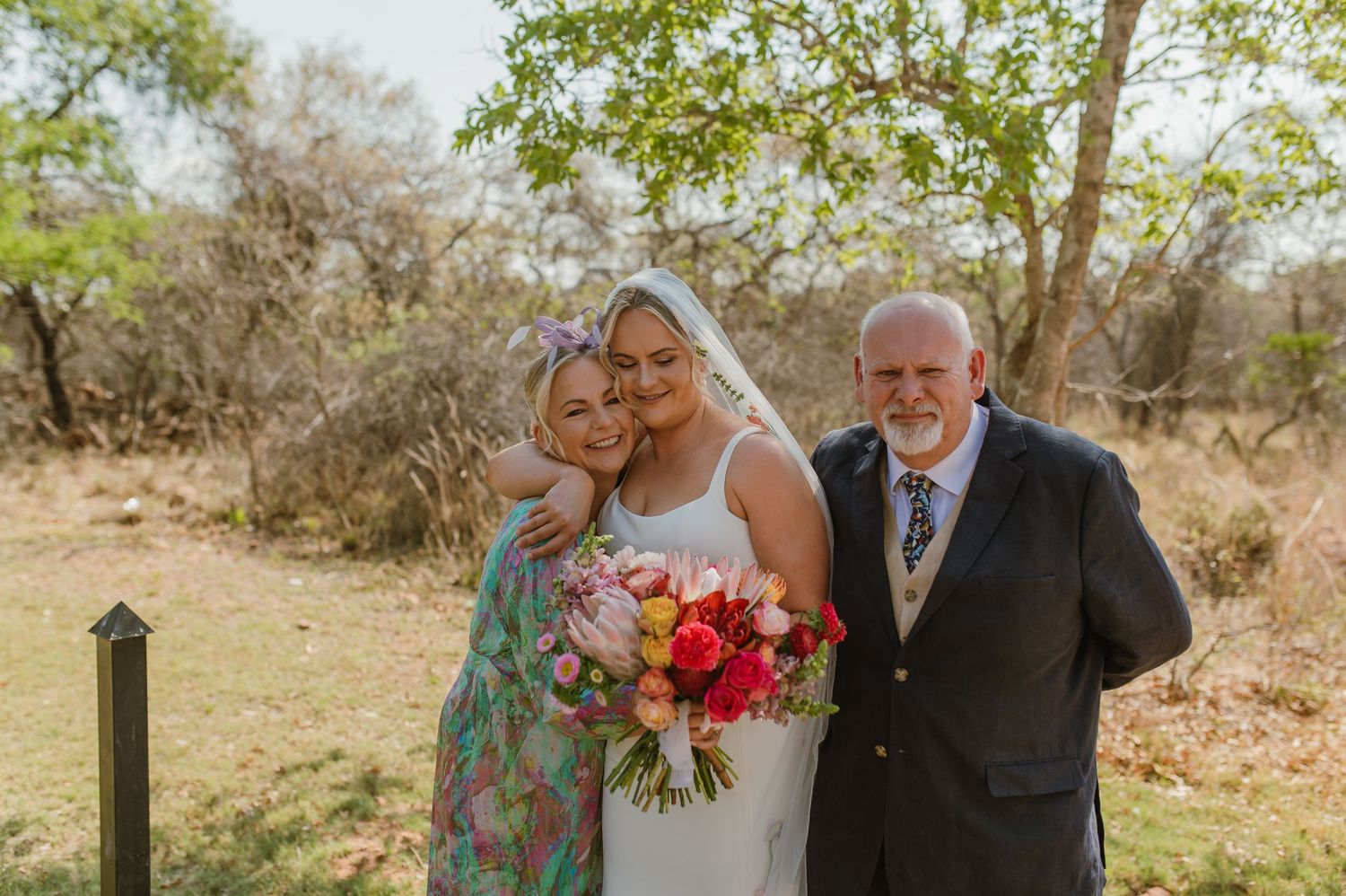 Emotional wedding moment captured in natural outdoor setting with trees.