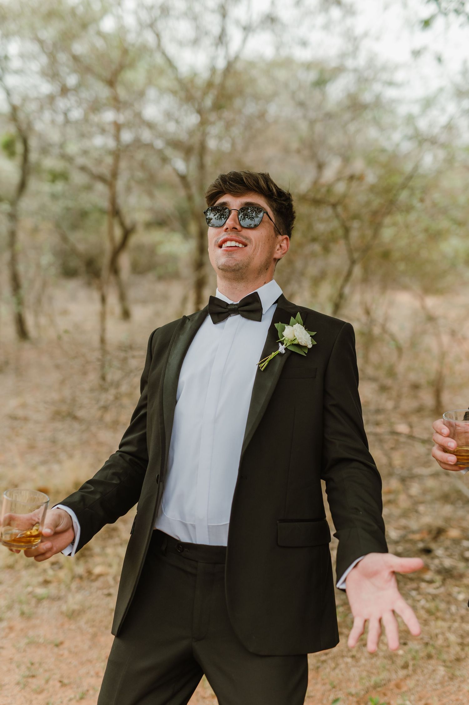 Wedding party members in formal attire striking animated poses in an outdoor setting.