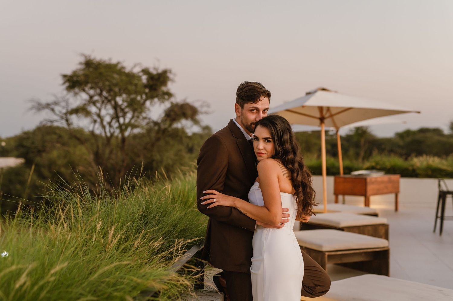Wedding couple poses on outdoor patio with scenic desert landscape views.