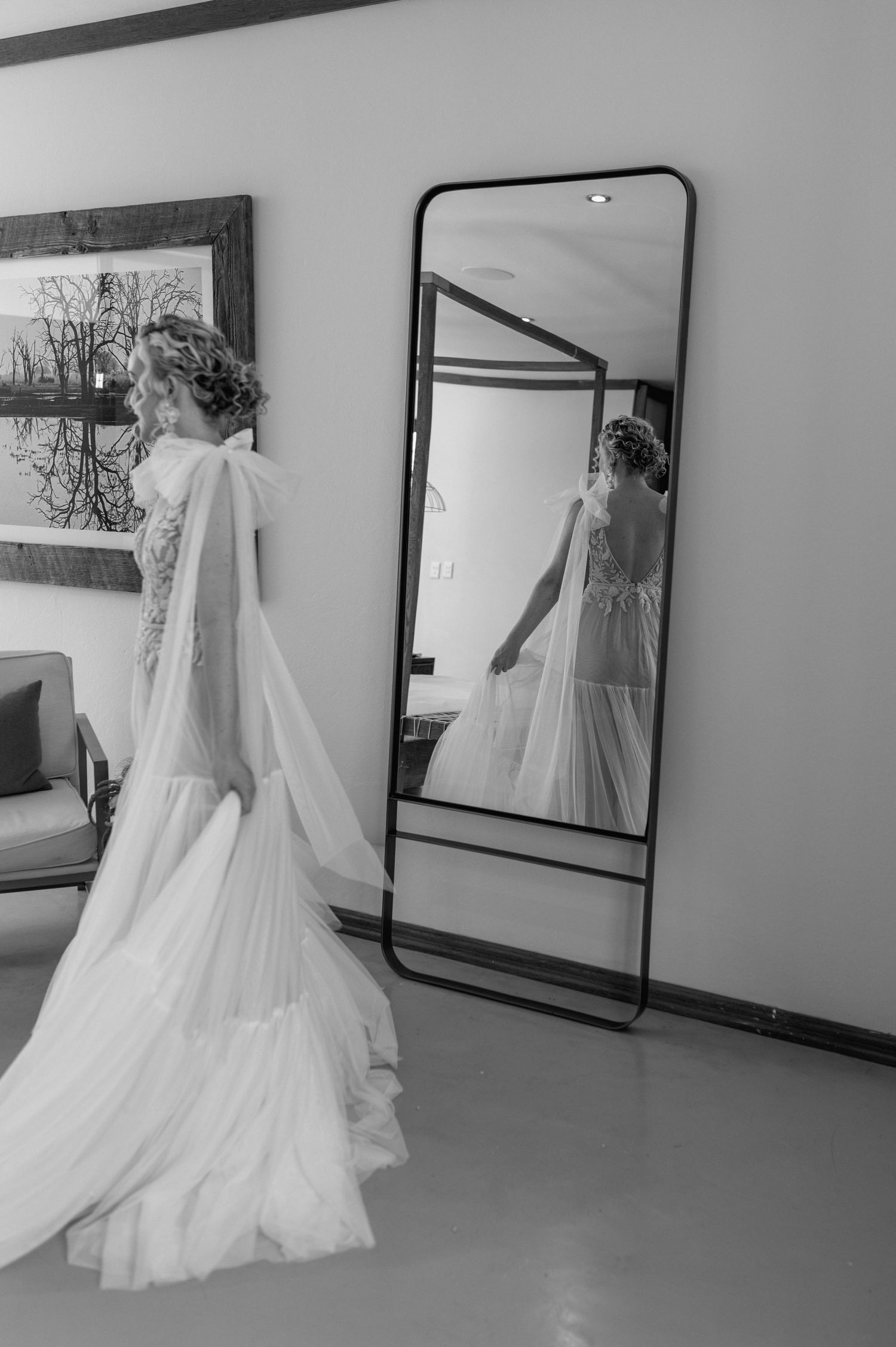 A bride in a flowing white gown poses in front of multiple mirrors.