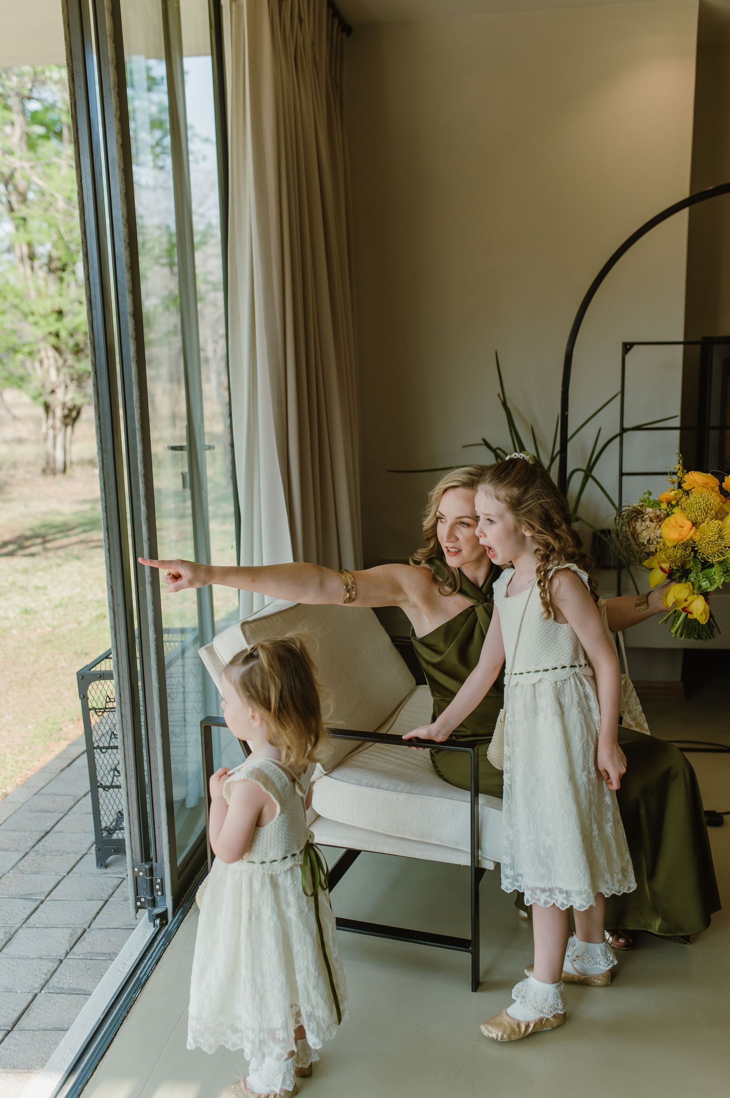 Playful wedding day moments captured near large windows with yellow floral accents.