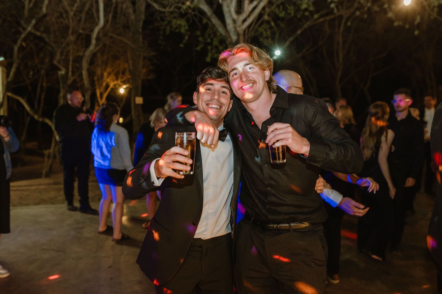 Wedding guests celebrating and dancing at nighttime outdoor reception.
