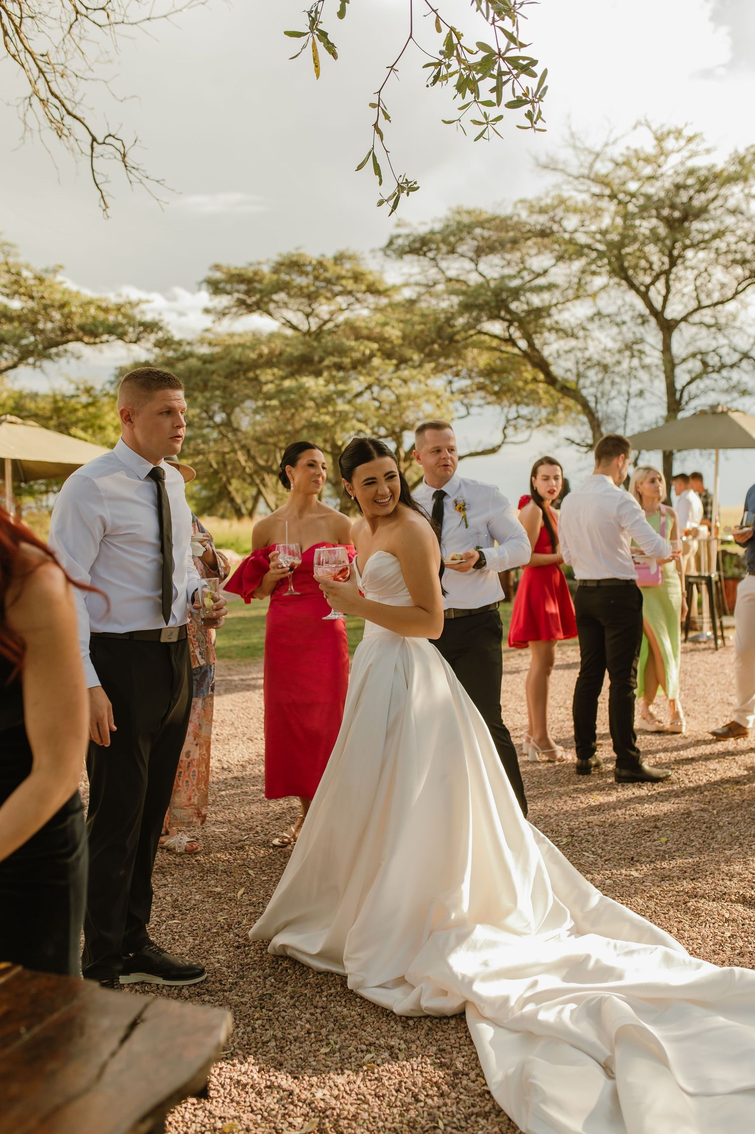 Bride in elegant white ball gown socializing with guests at an outdoor wedding reception.
