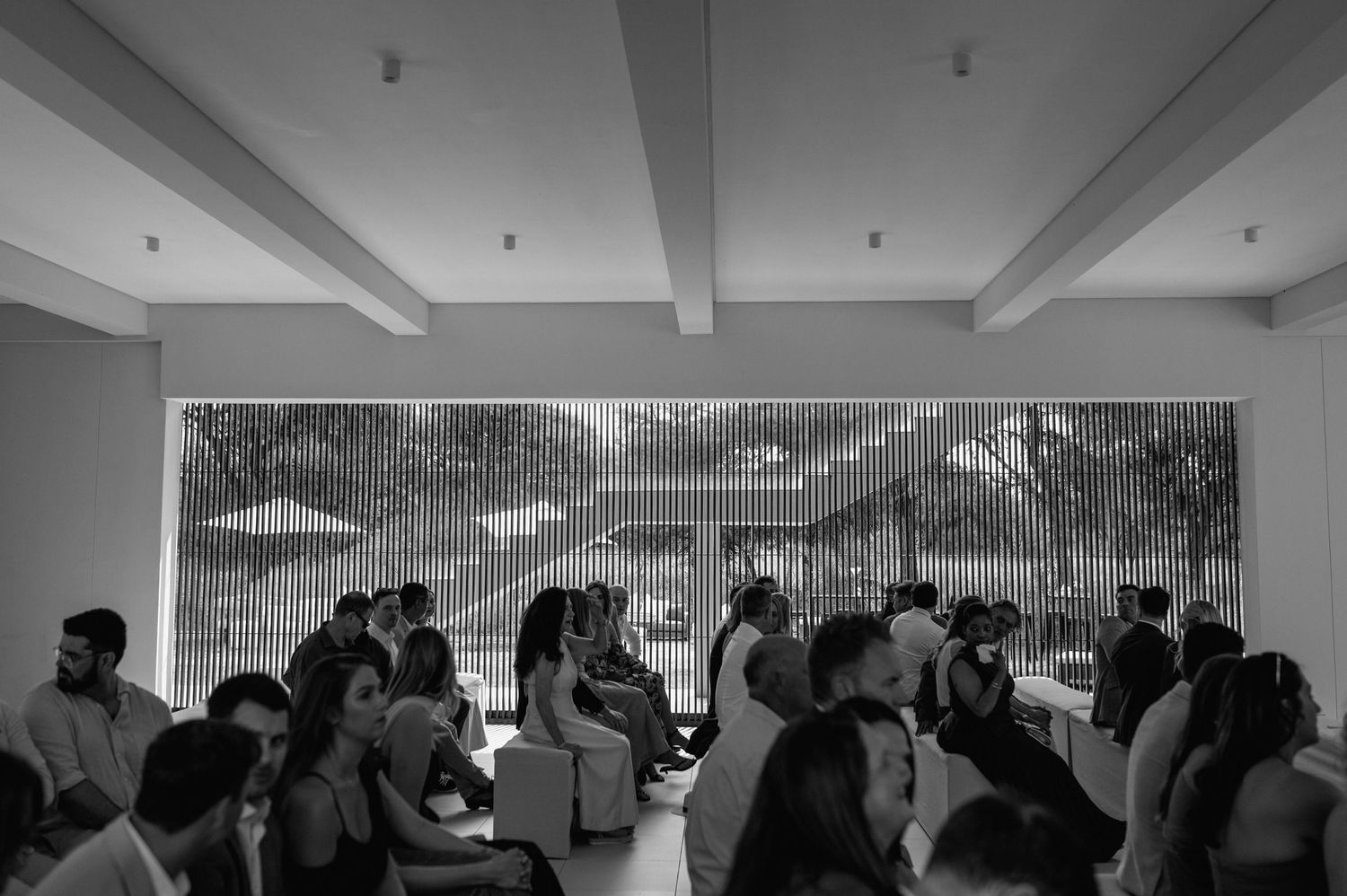 A panoramic collage of people gathered in a room with white walls and beamed ceilings.