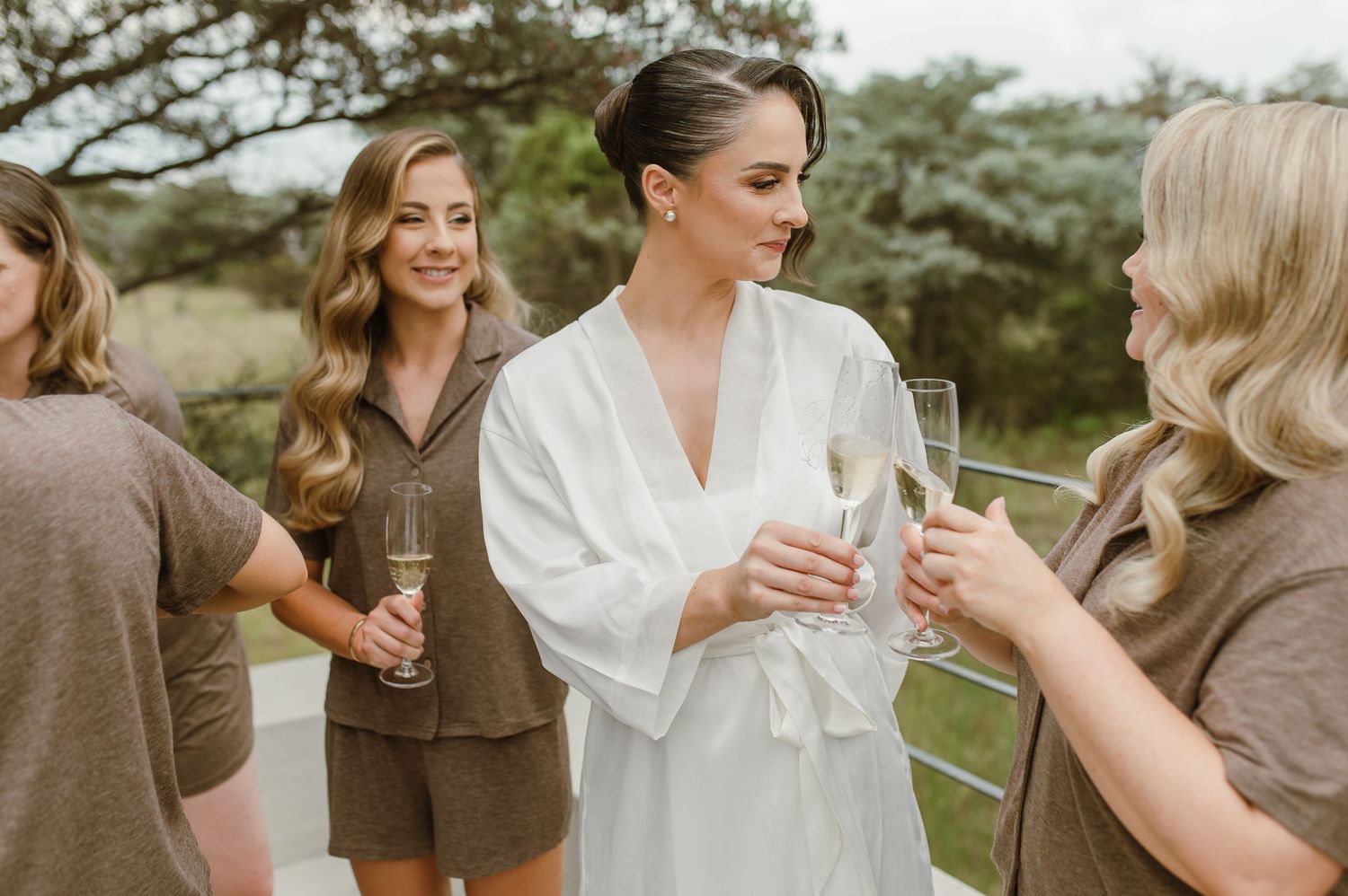 A group enjoying champagne outdoors while wearing casual attire and robes during a celebration.