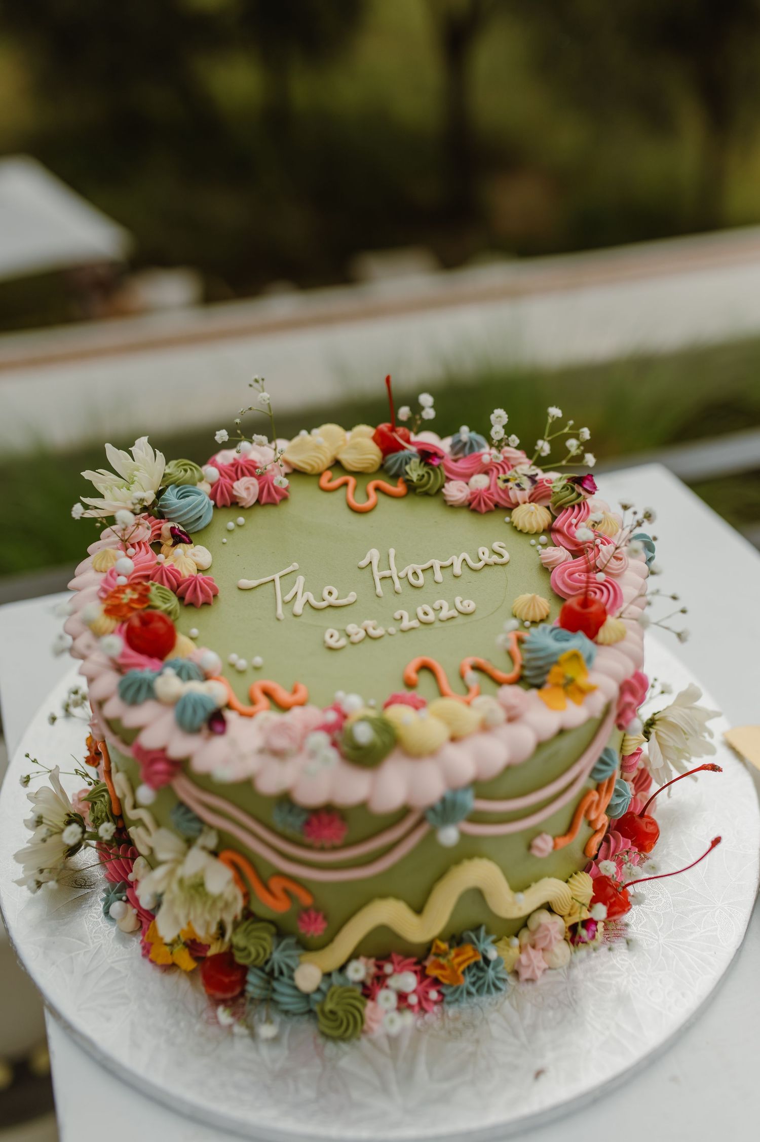 Wedding cake decorated with delicate pink flowers and colorful accents on a white base.