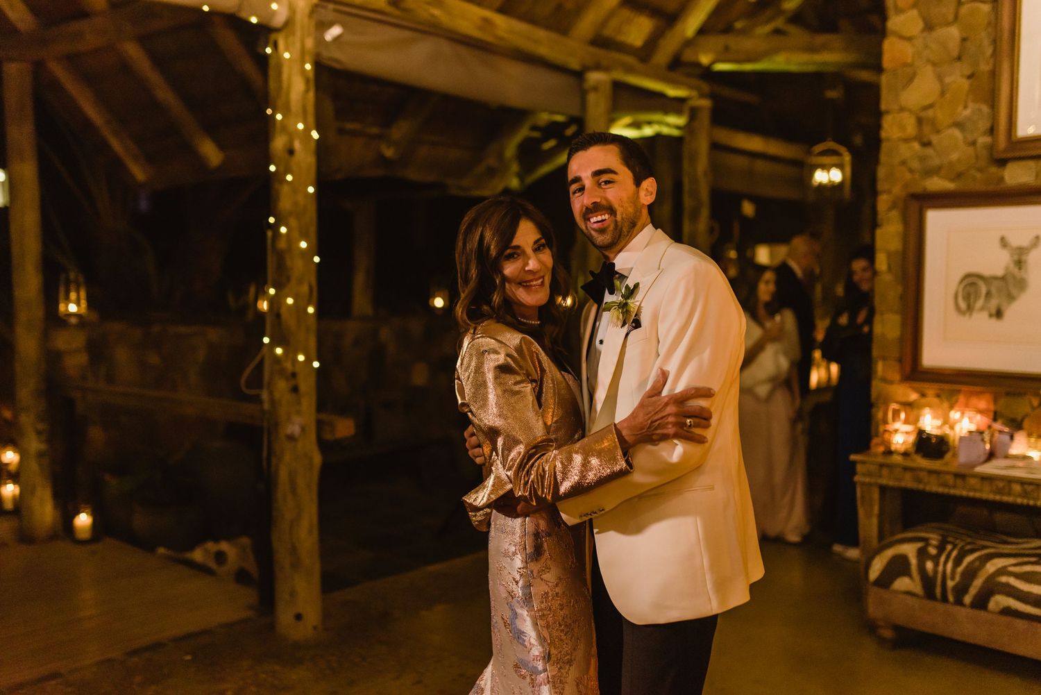 Couples dancing under string lights in rustic barn wedding venue.