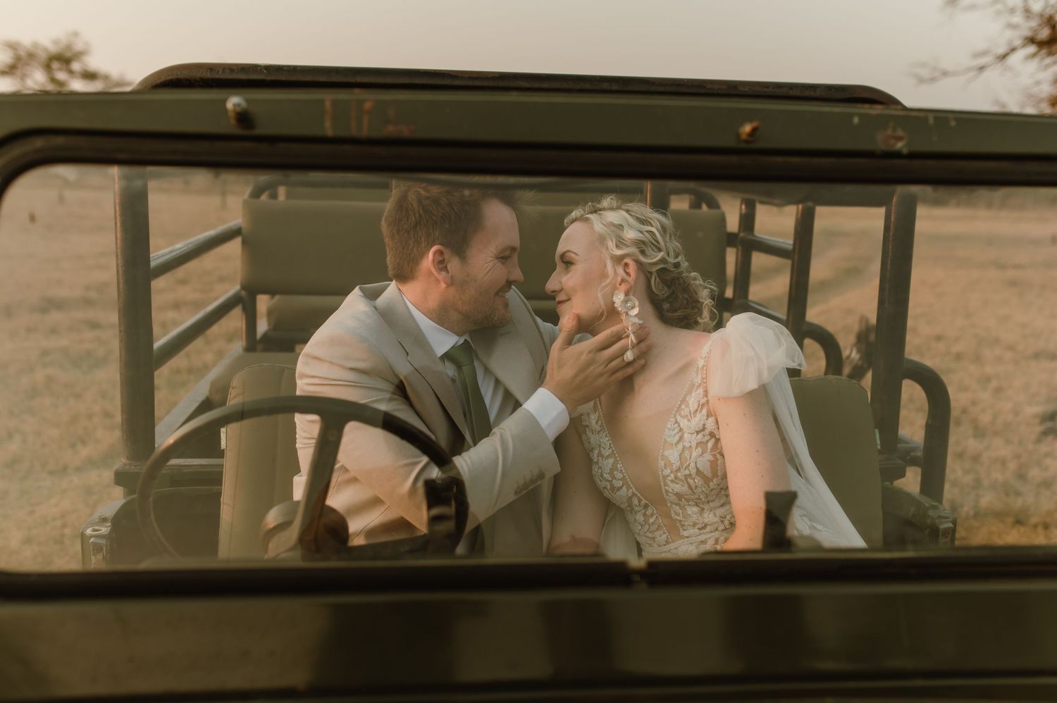 Newlyweds share tender moments through the windows of a classic safari vehicle.