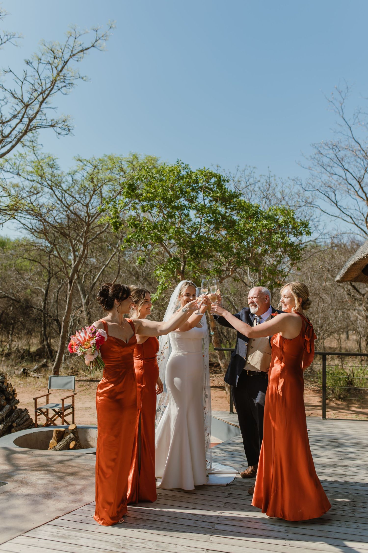 Wedding celebration with bridal party in orange dresses dancing on an outdoor patio.