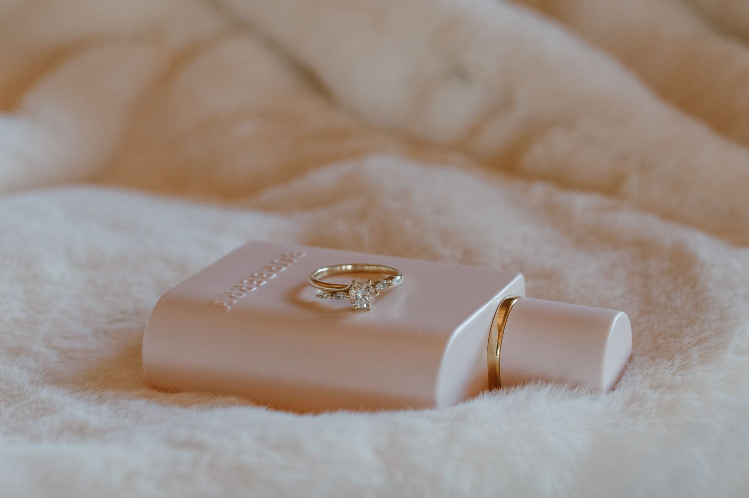 Wedding rings displayed on light pink fabric with soft natural lighting.