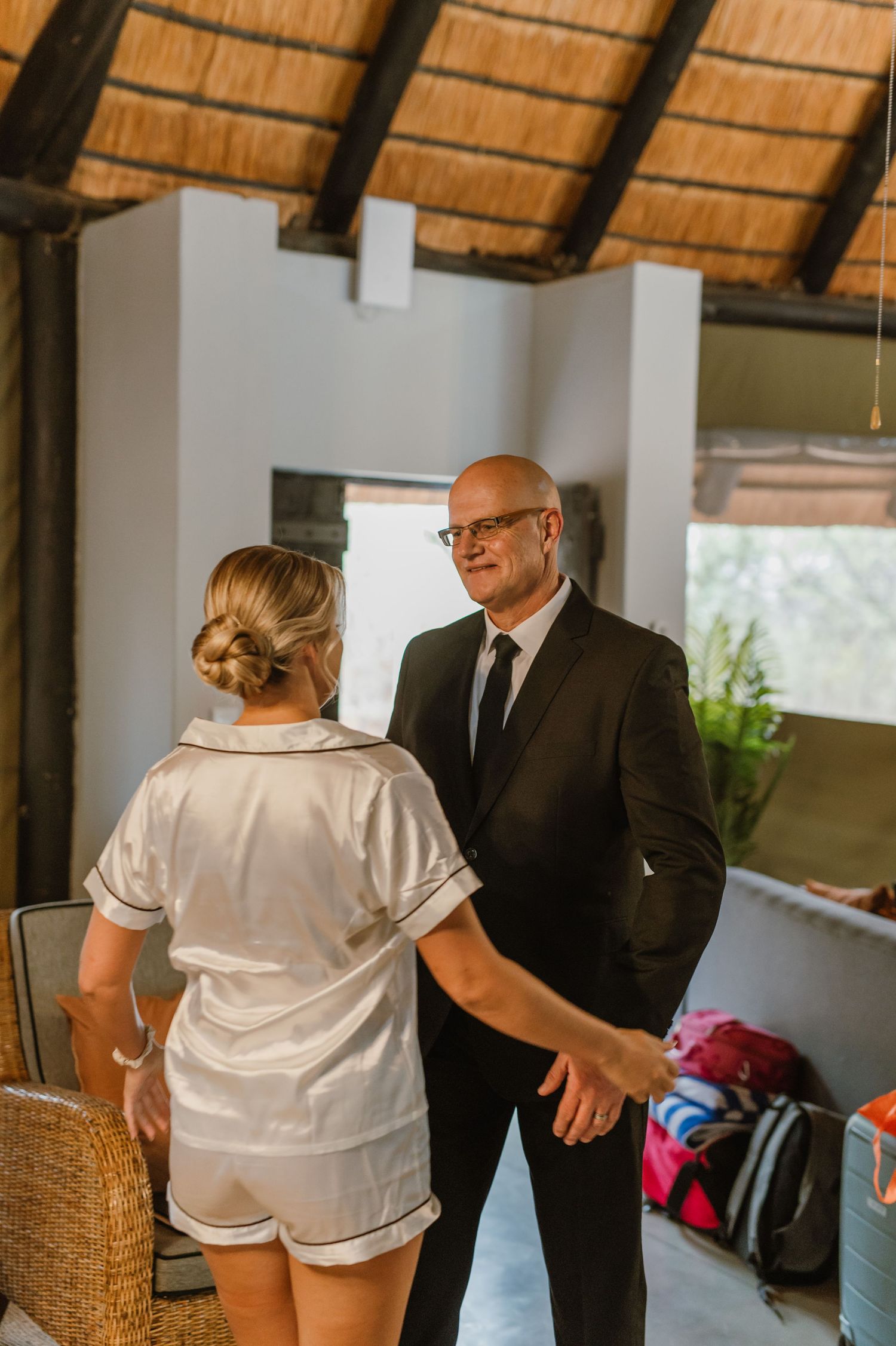 Indoor scene with thatched roof showing preparation moments before an event.