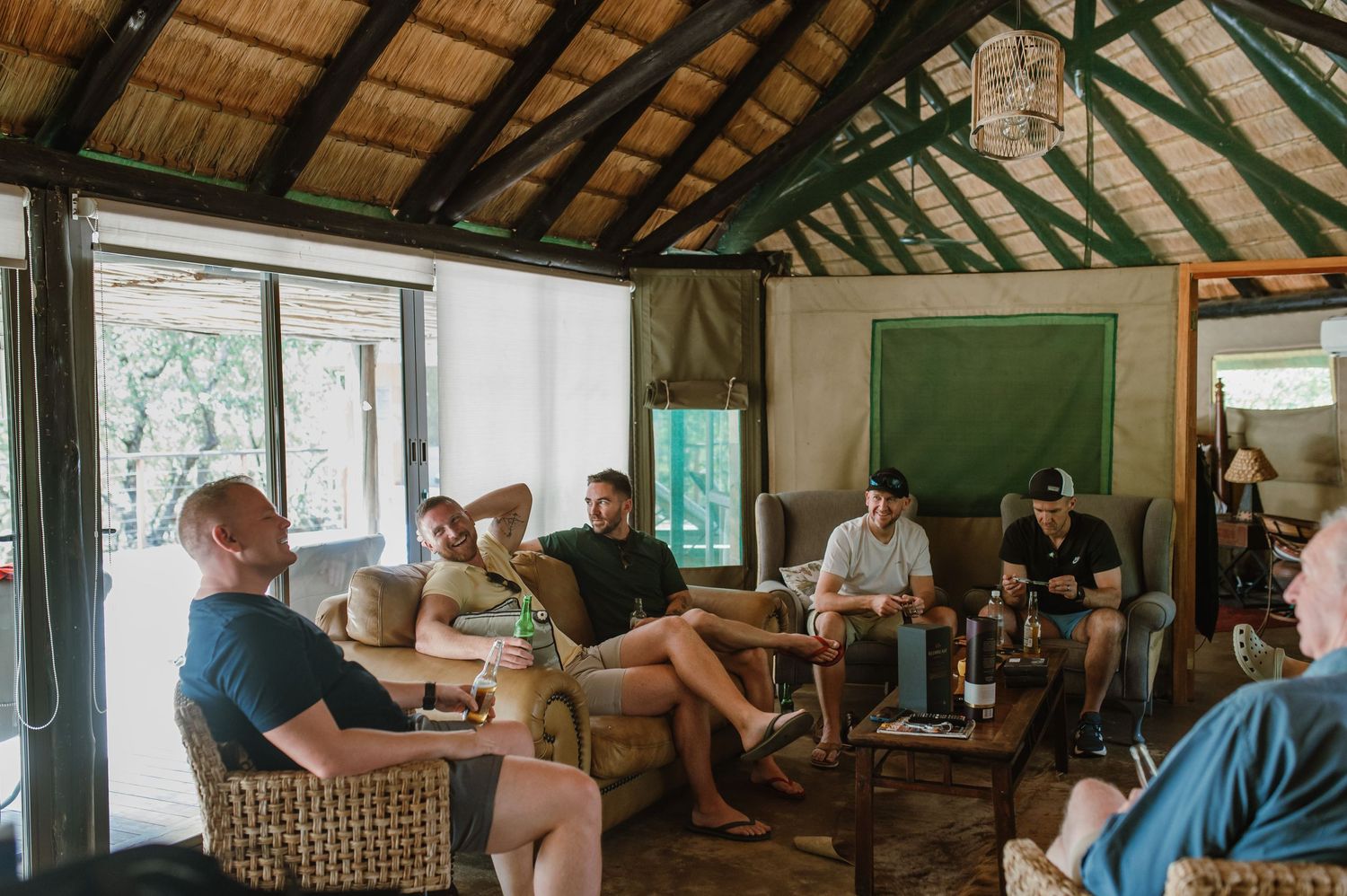 Interior of safari lodge common area with wooden beams and casual seating.