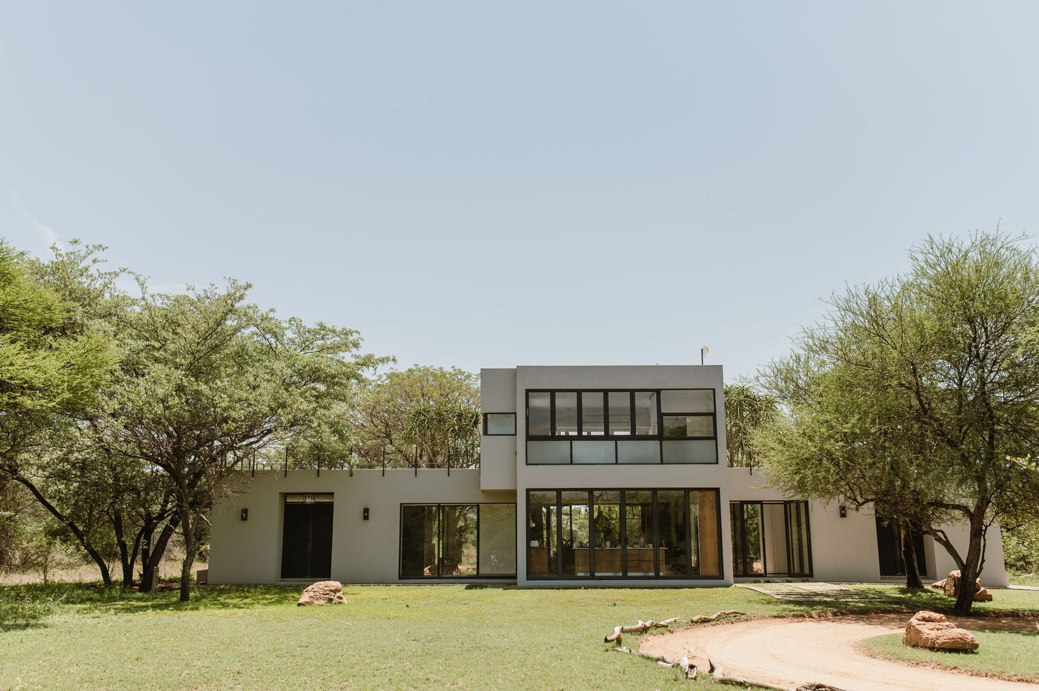 Modern white architectural building with large windows set in a natural desert landscape.