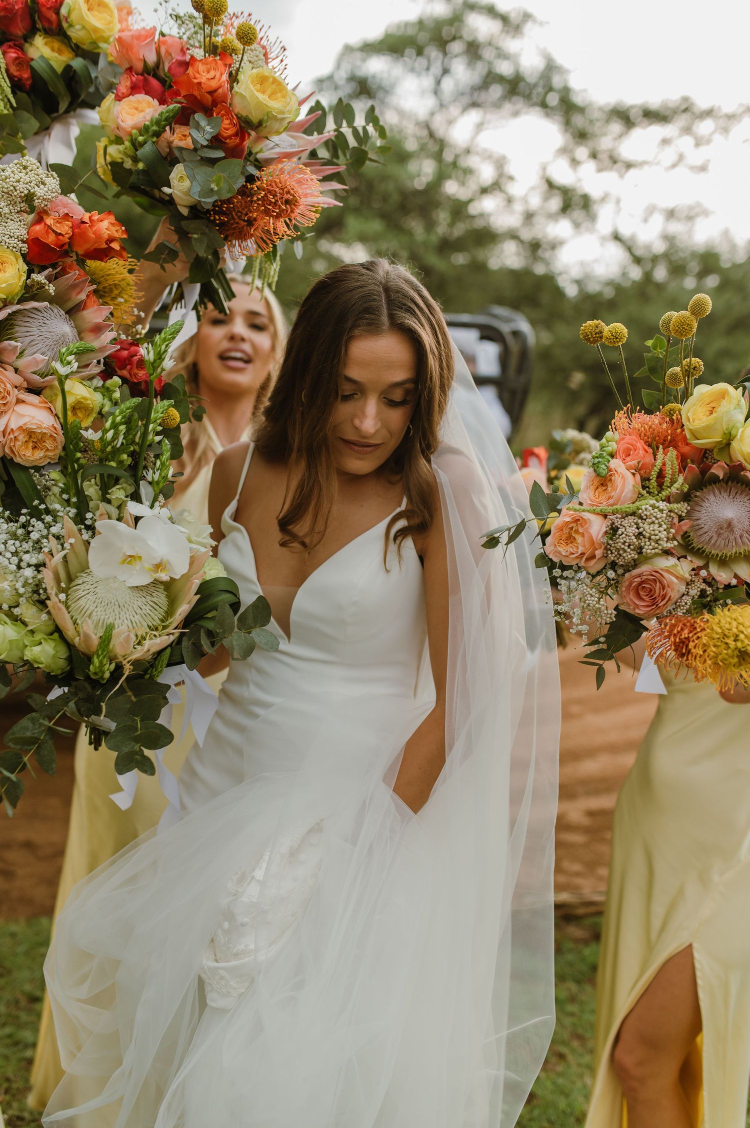Romantic bridal portrait amidst lush floral arrangements in coral and yellow tones.