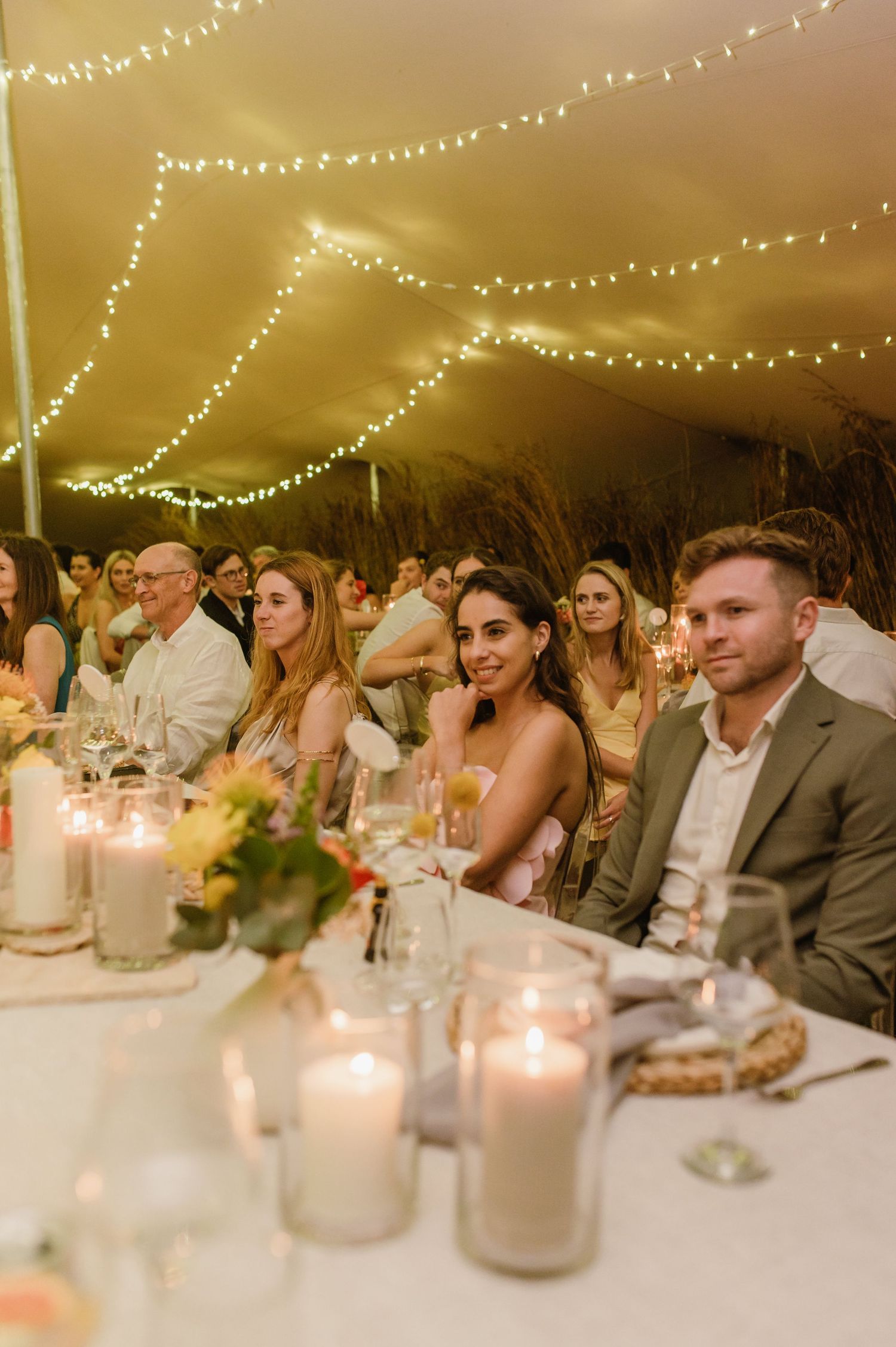 Candlelit reception tables decorated with floral centerpieces and glowing string lights above.