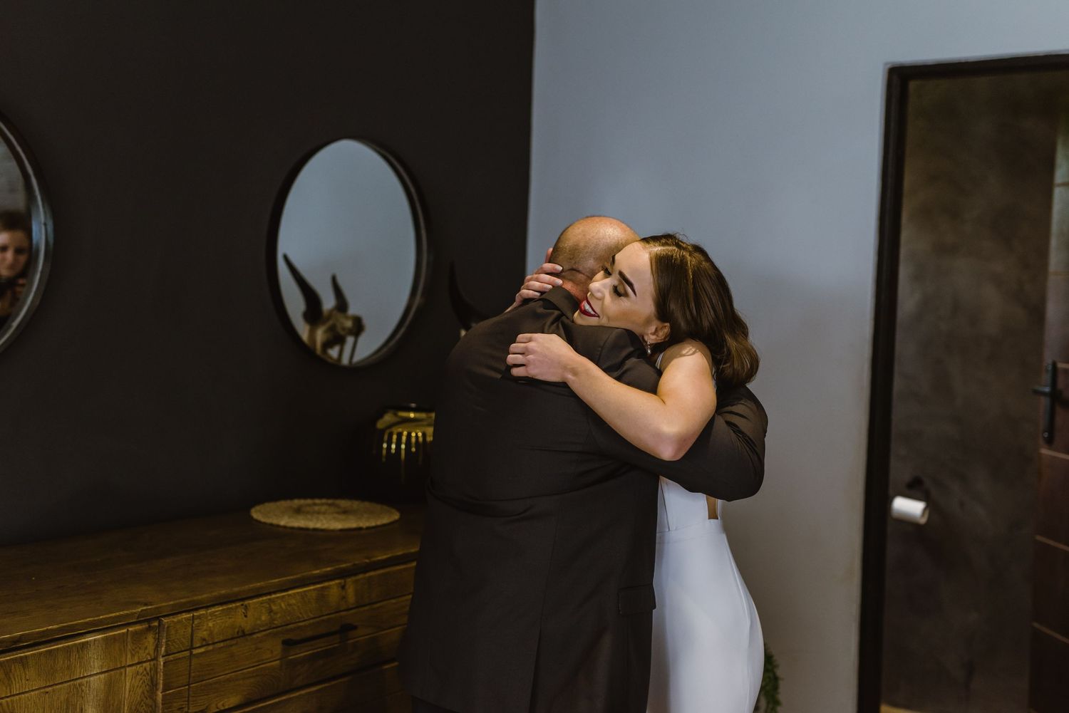 Wedding celebration captured in a room with wooden furniture and modern decor.