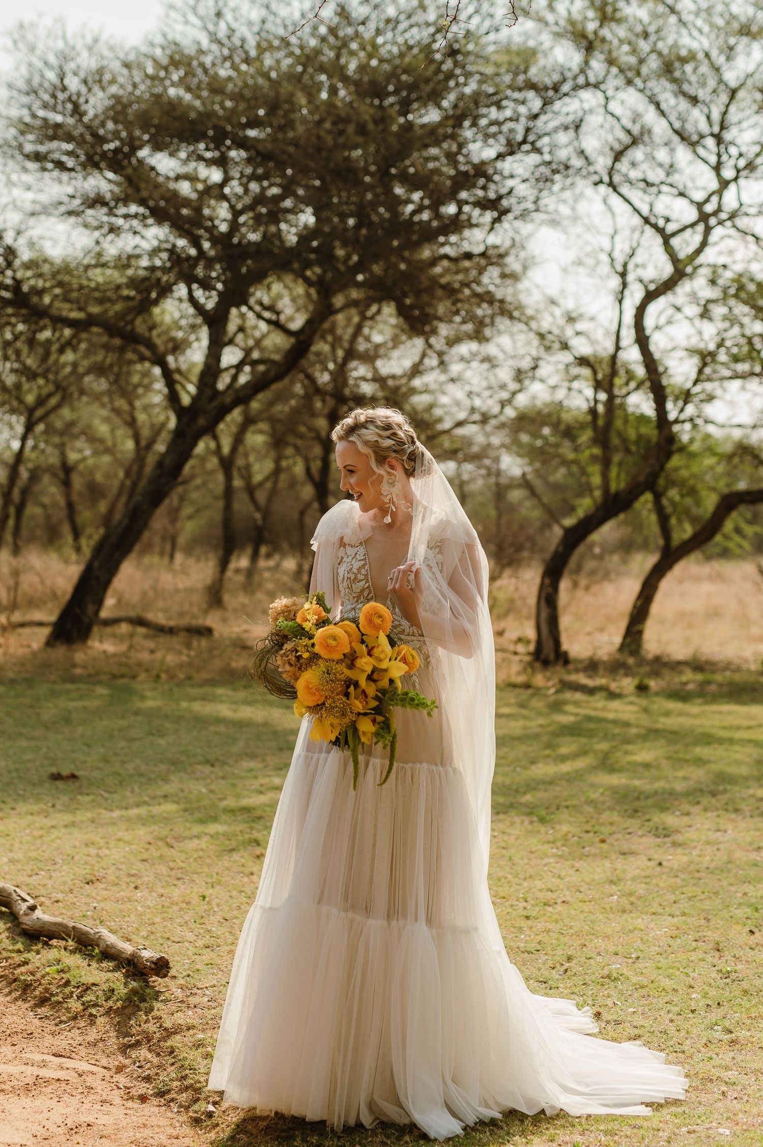 A wedding dress with sunflowers displayed in a natural outdoor setting with trees.