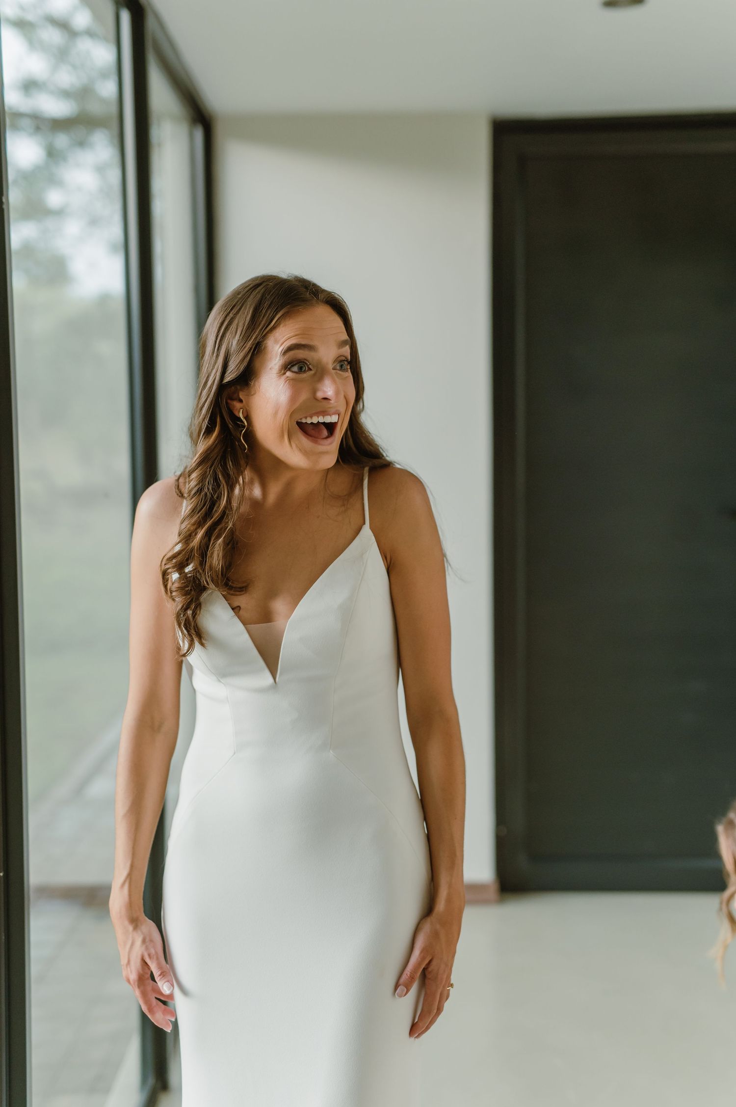A joyful moment captured in a bright room as someone wearing a white dress laughs expressively.