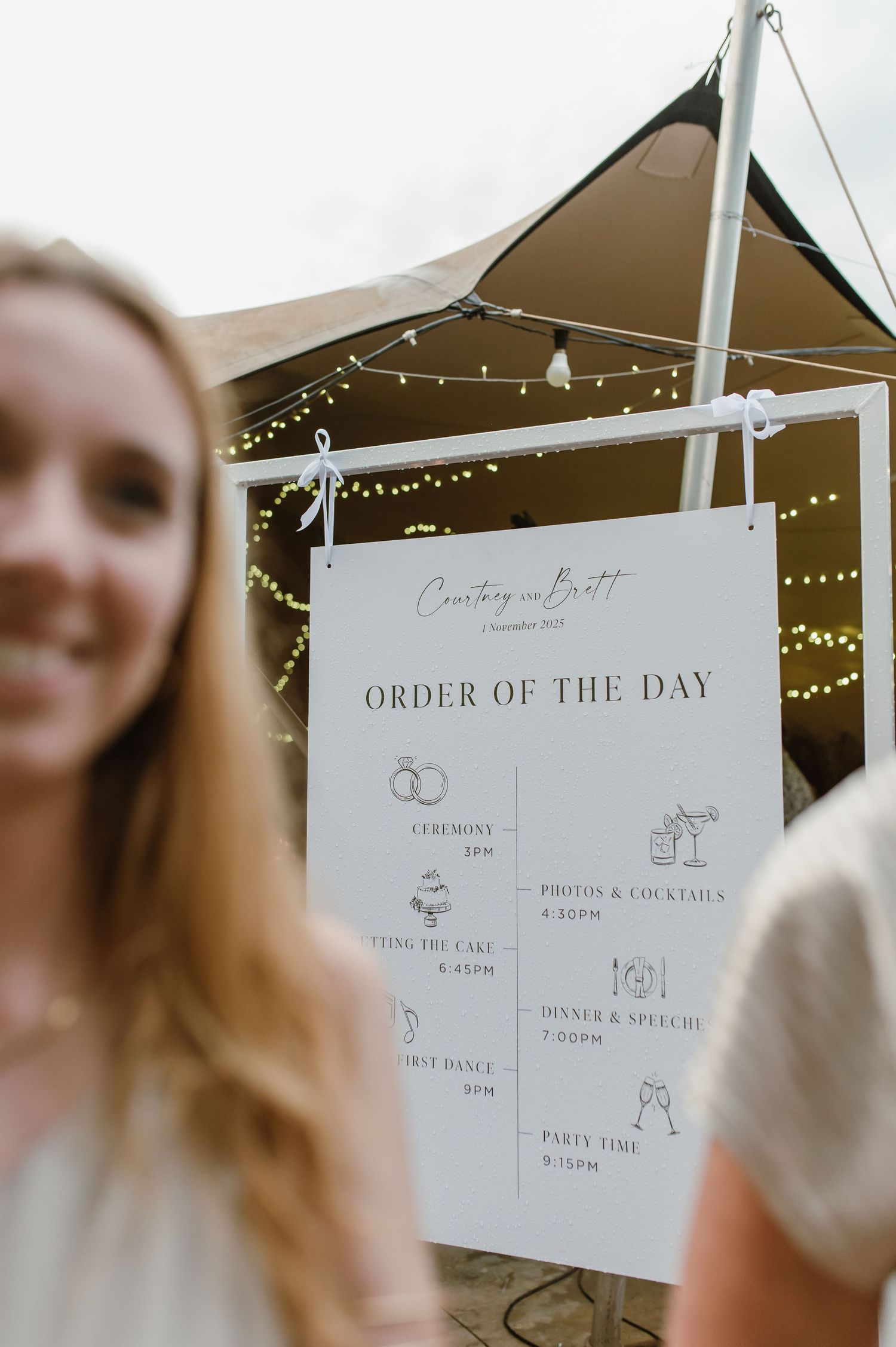 Wedding timeline schedule displayed on white signs at an outdoor venue.