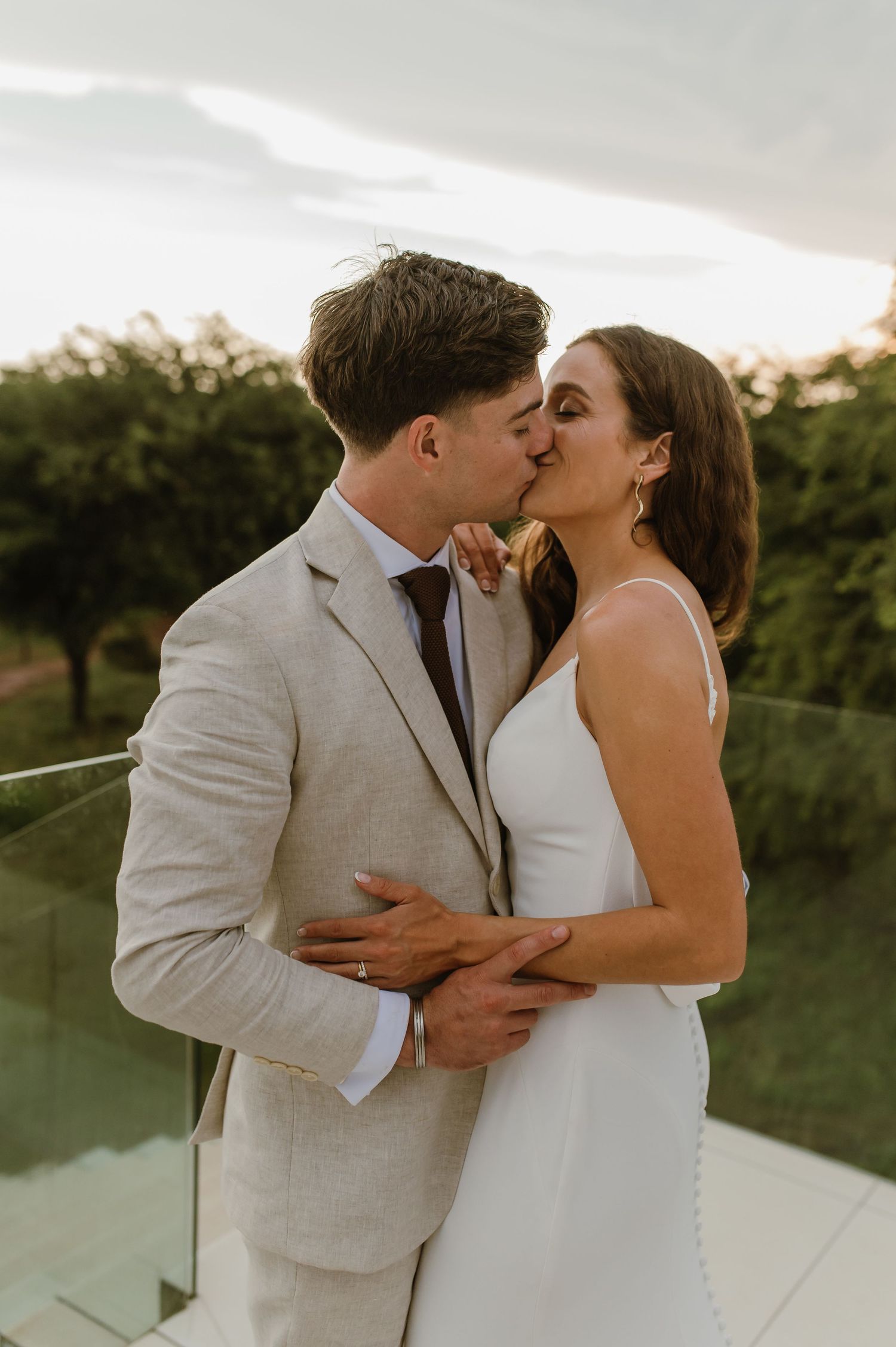 Romantic sunset kiss between newlyweds on an outdoor balcony.