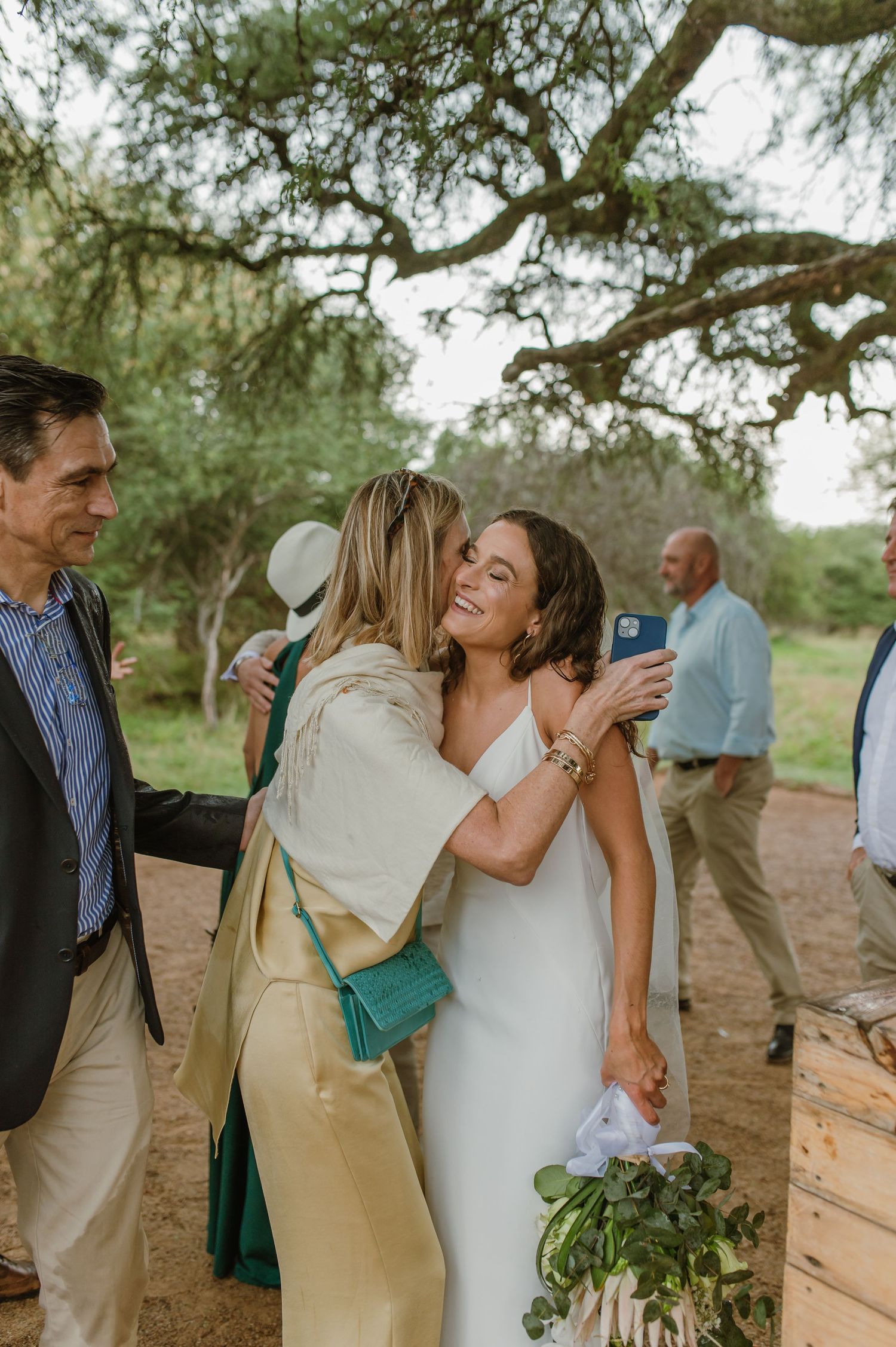 Guests sharing hugs and joyful moments at an outdoor wedding reception.