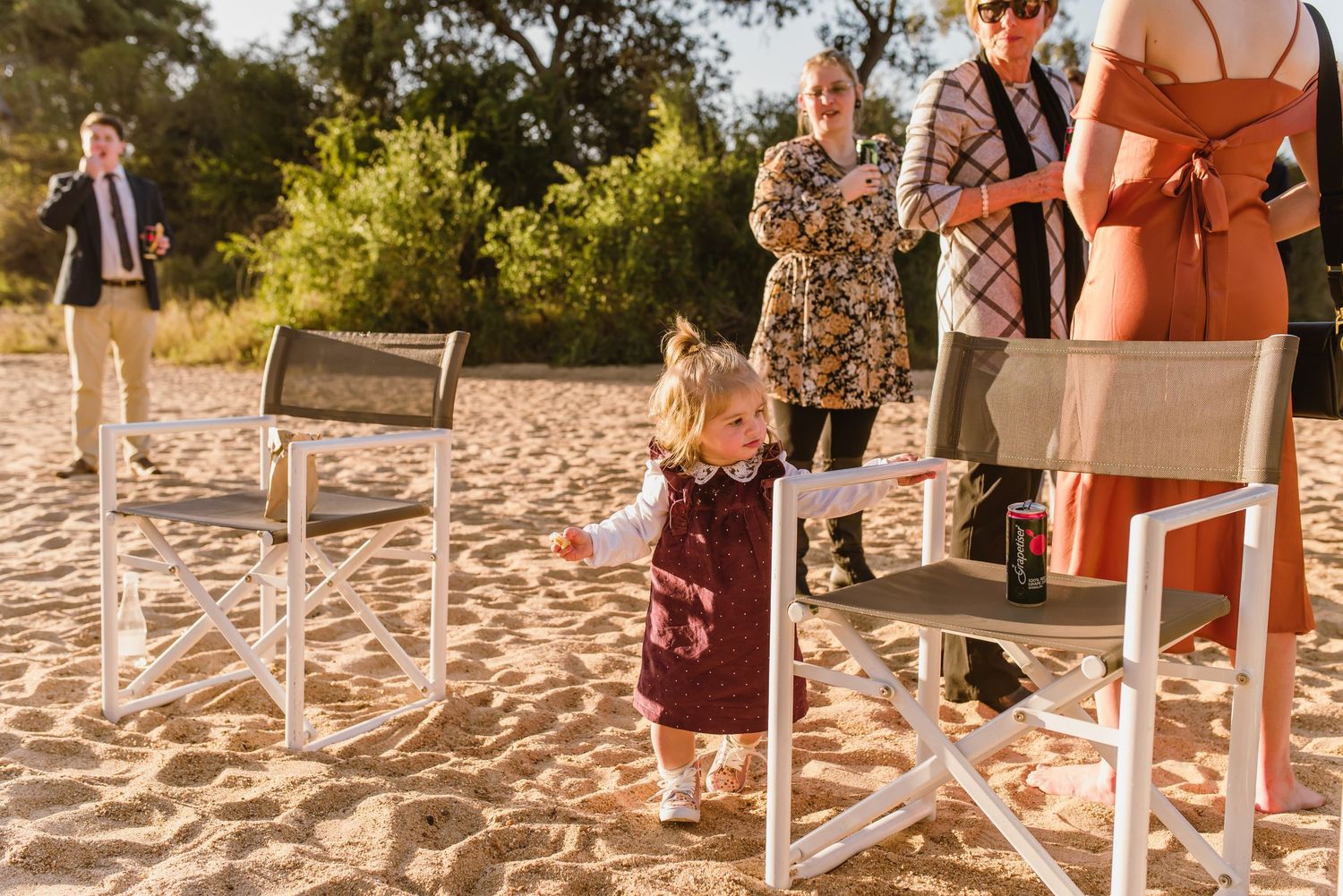 White chairs arranged in rows on a sandy beach for outdoor ceremony.