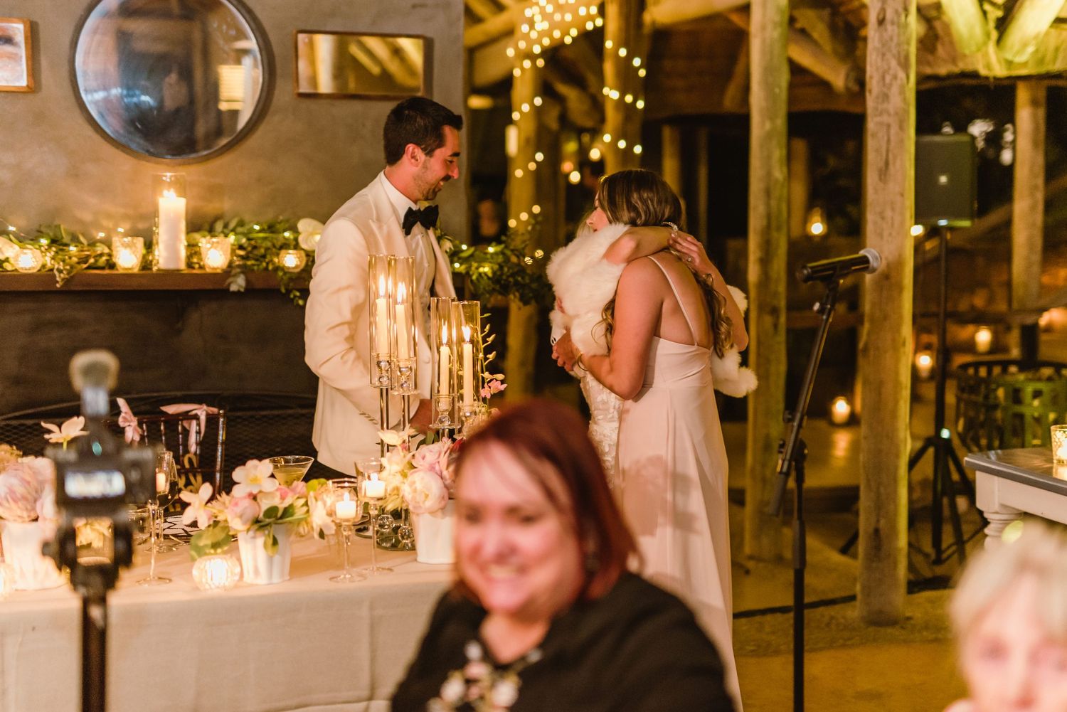 Intimate moment captured during wedding reception with candlelit tables and string lights.
