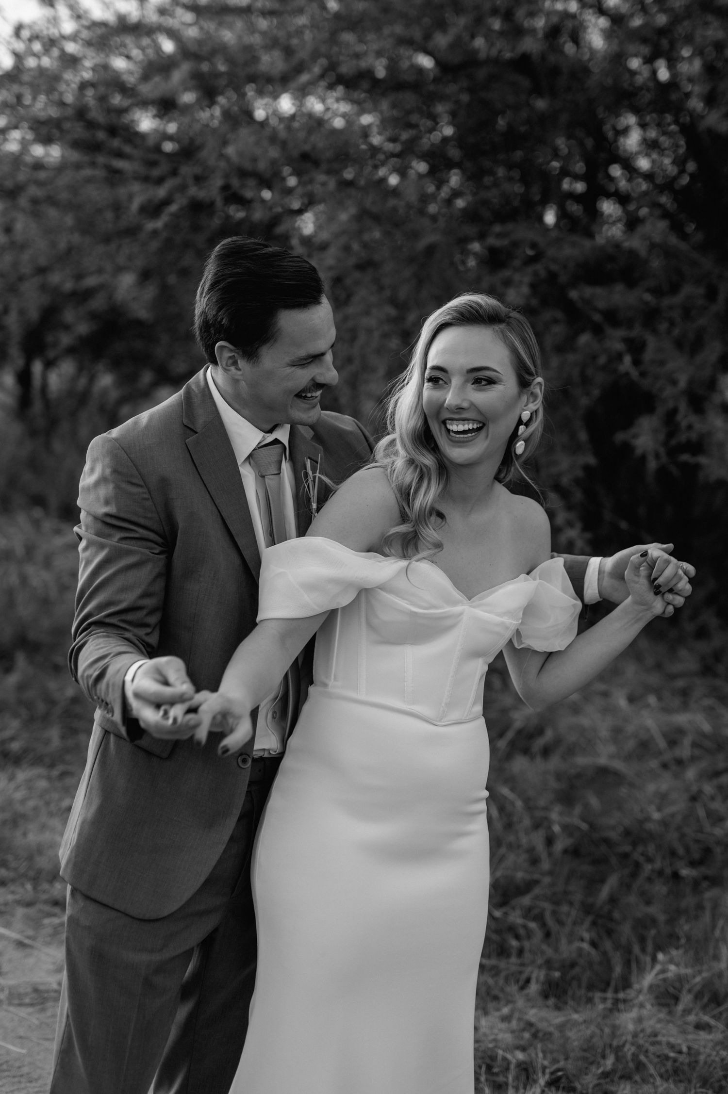 Black and white photo of a couple sharing a joyful moment during their wedding photoshoot.