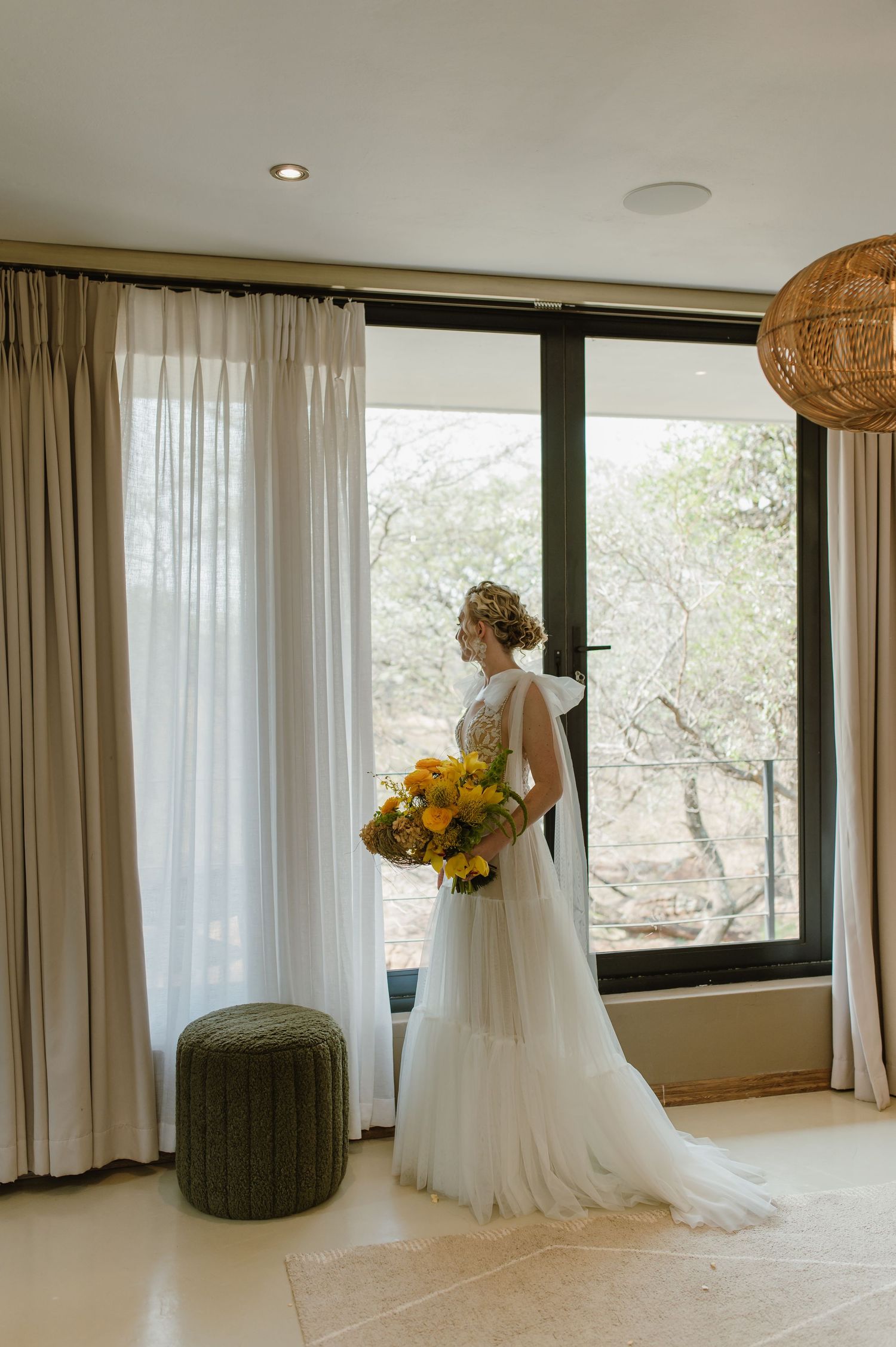 Sunlit bridal portraits in a modern room with floor-to-ceiling windows and natural decor.