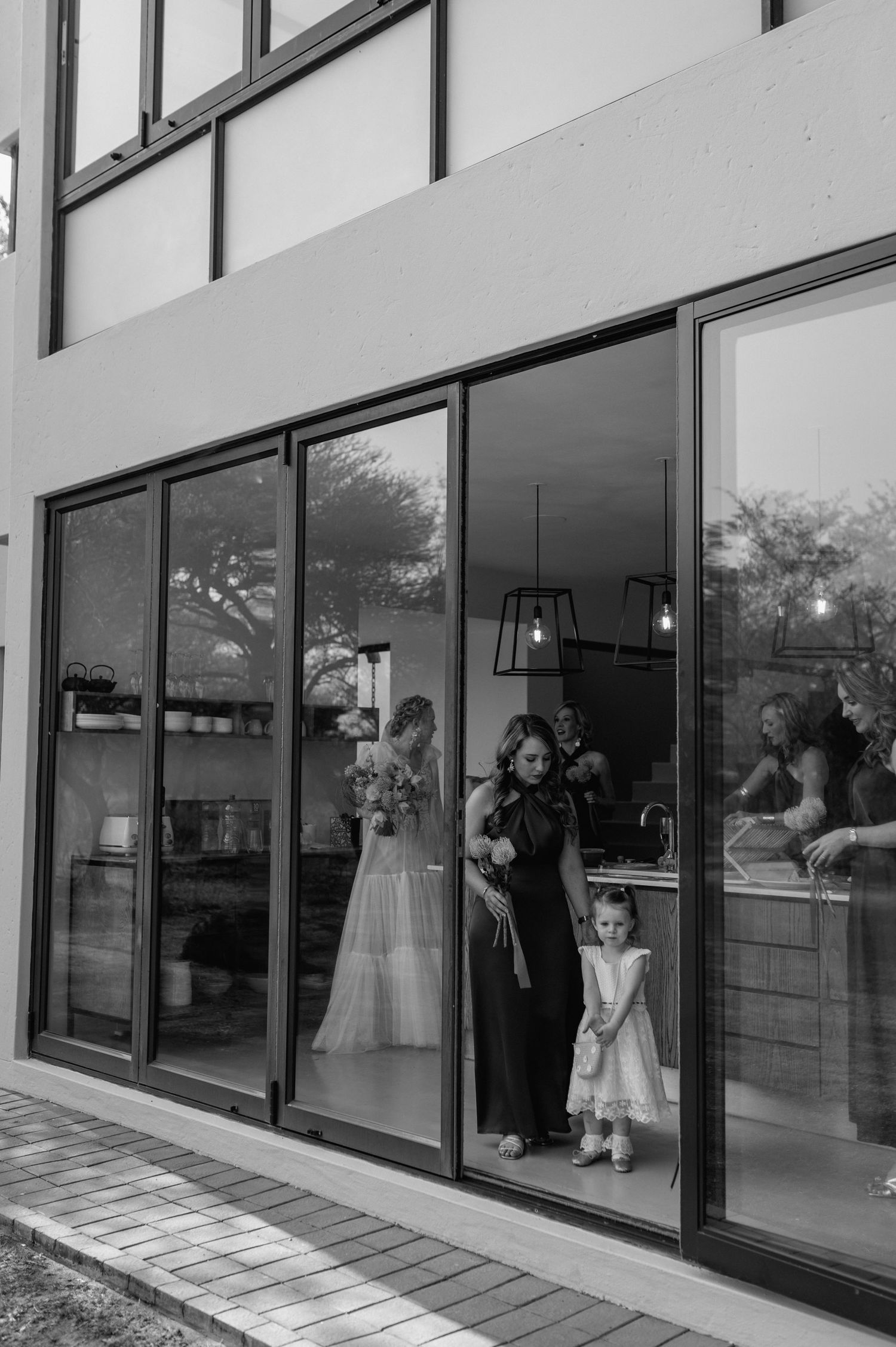 Wedding party poses by large glass windows in a modern building.