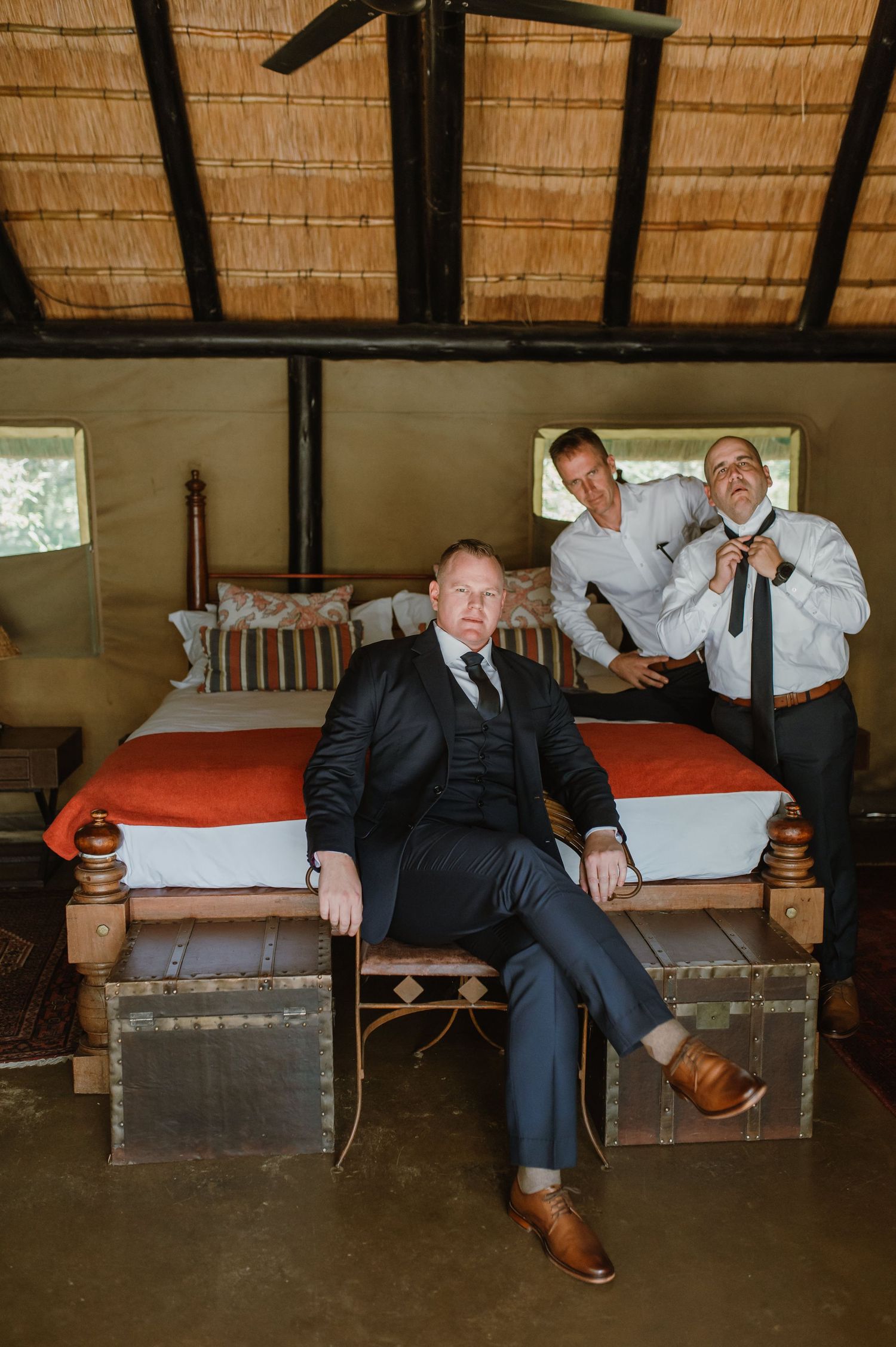 Groomsmen relaxing on vintage trunks in a rustic lodge setting.