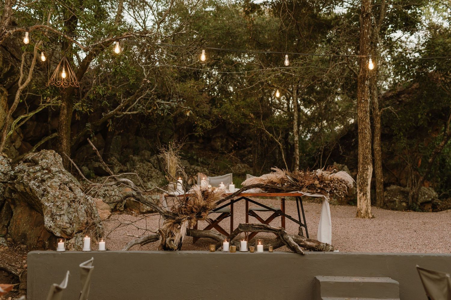 Long banquet tables arranged outdoors with string lights creating an enchanting dining setting.