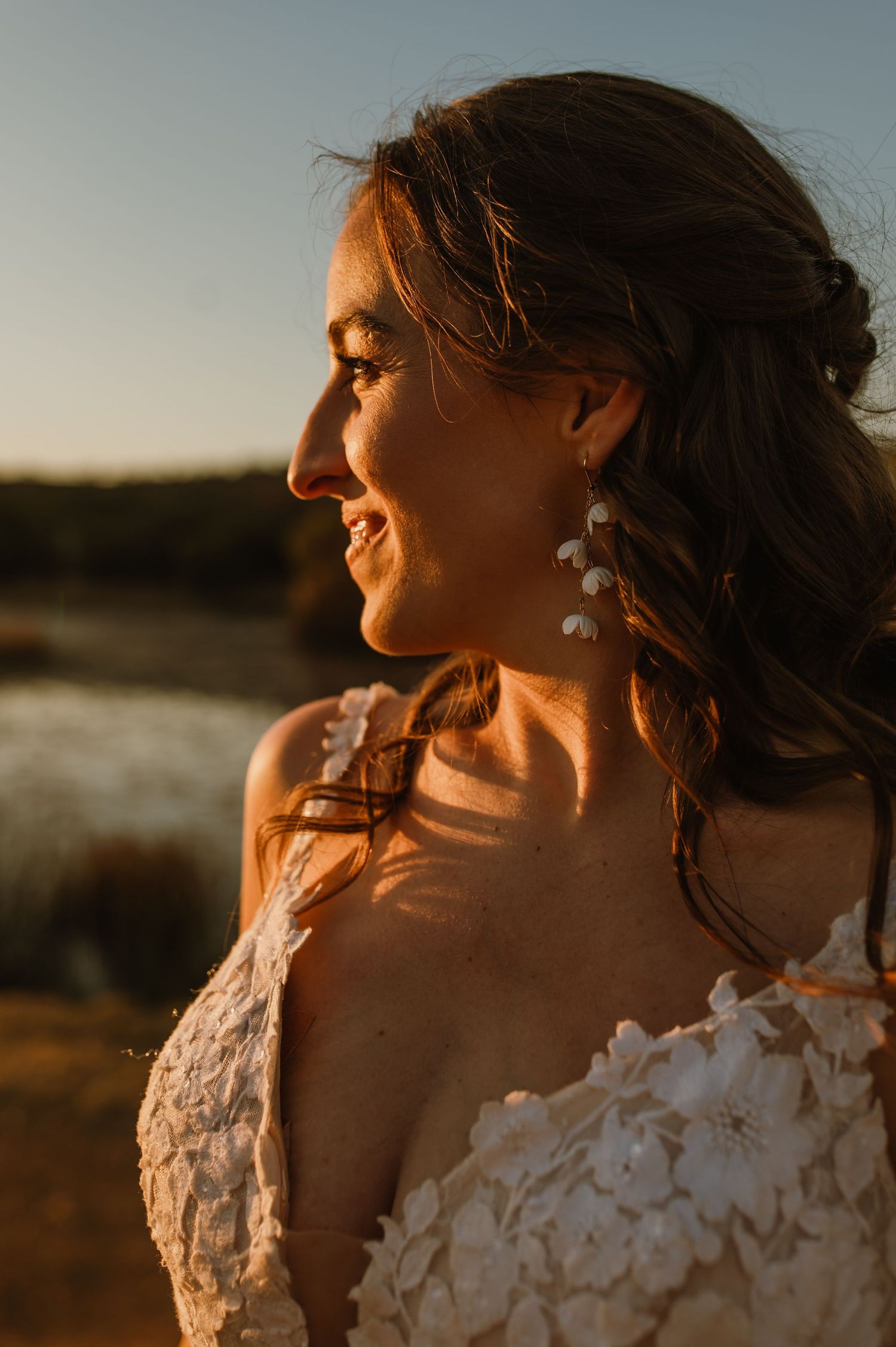 Close up profile view of a bride in lace dress during sunset with warm golden lighting.
