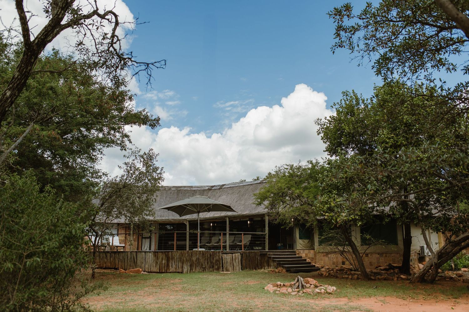 Wide angle view of a ranch property with oak trees and buildings under blue sky.