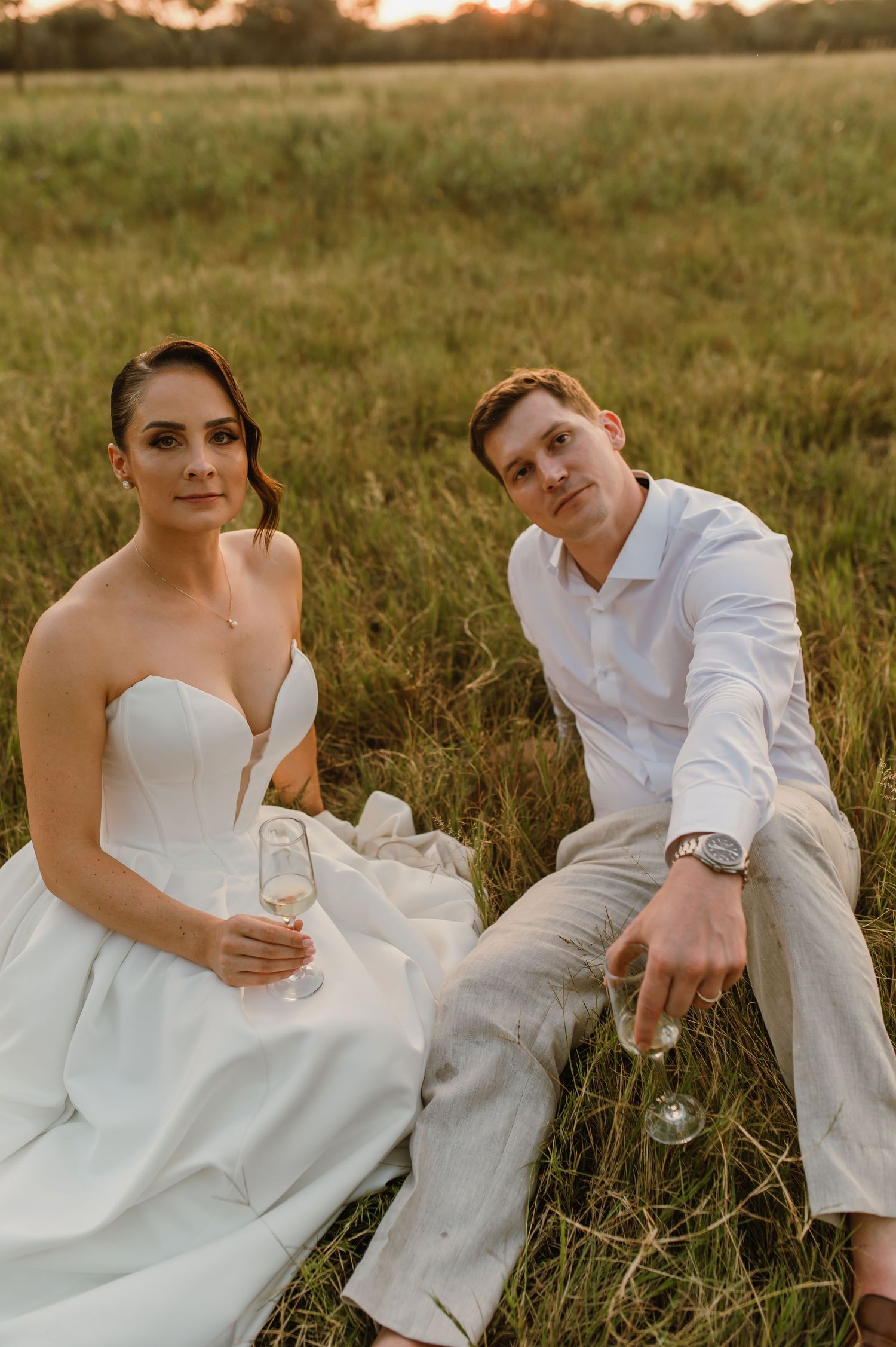 A couple relaxes in the grass during their sunset wedding photography session.