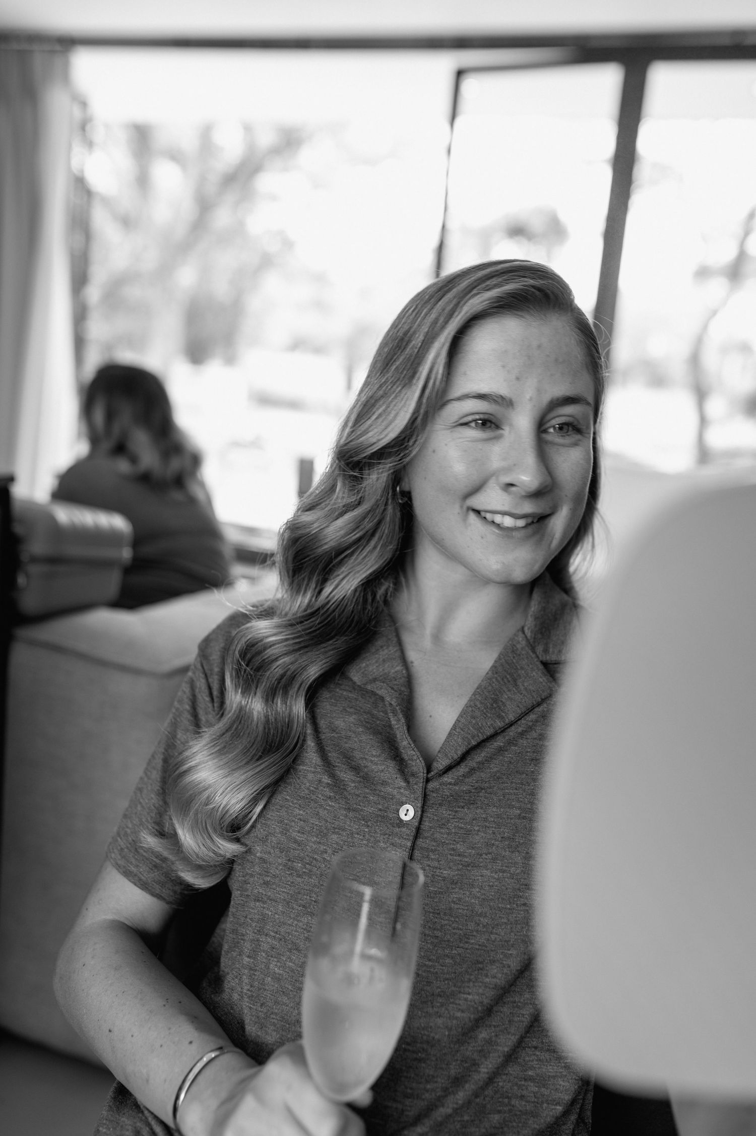 Black and white portrait of a person holding a champagne glass in a casual setting.